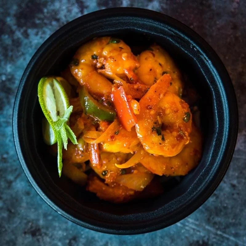 A bowl of shrimp curry garnished with lime