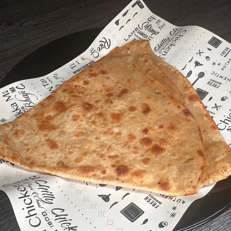 Two slices of cheese pizza on printed paper-lined black tray.