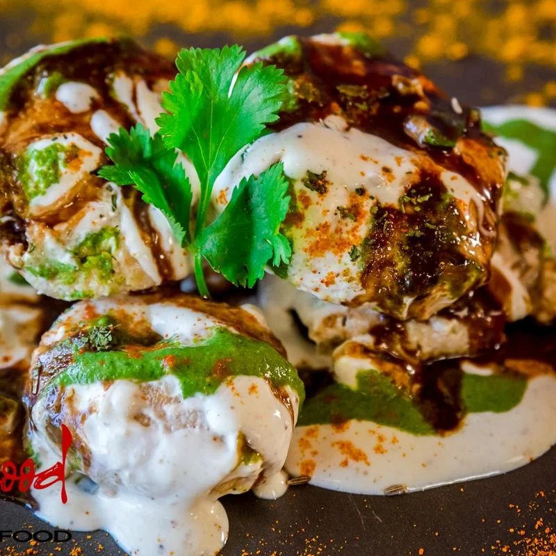 Lentil dumplings soaked in yogurt and topped with mint & tamarind chutney and Indian spices. | Vegetarian