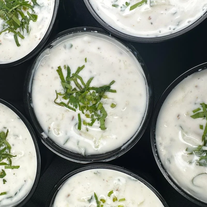 Containers of creamy soup garnished with chopped green herbs.