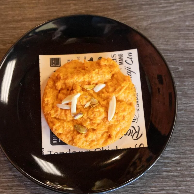 Fried chicken cutlet with sliced almonds and pumpkin seeds on top, served on a black plate with a piece taken out.