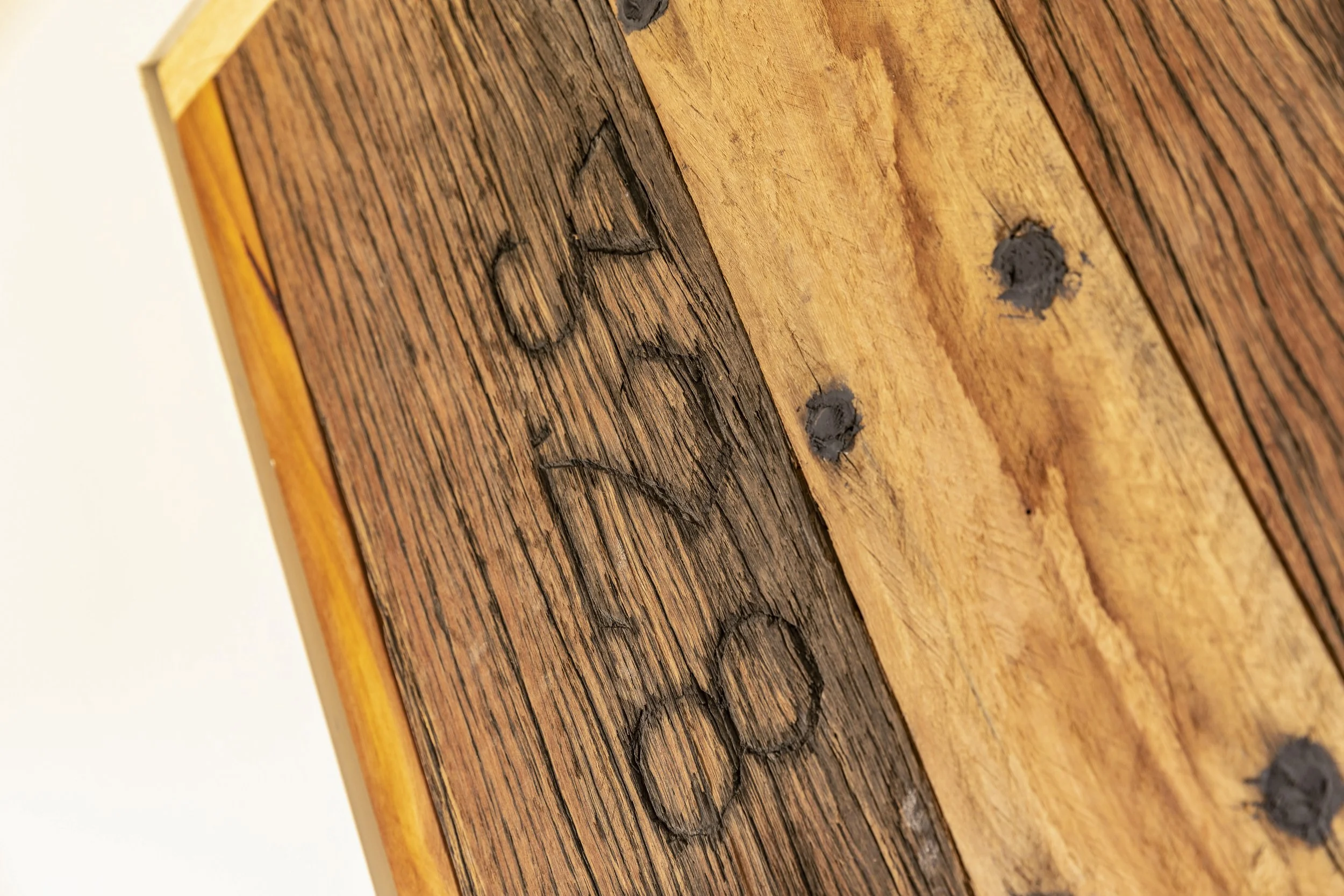 Close-up of a wooden surface with visible grain, cracks, and dark knots.