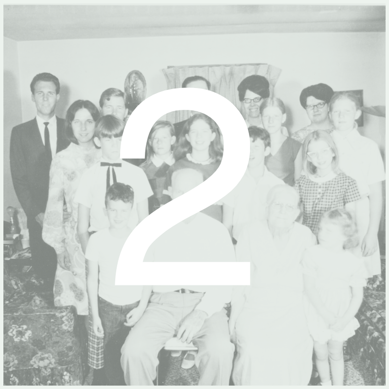 A black and white family portrait featuring multiple adults and children gathered in a living room.