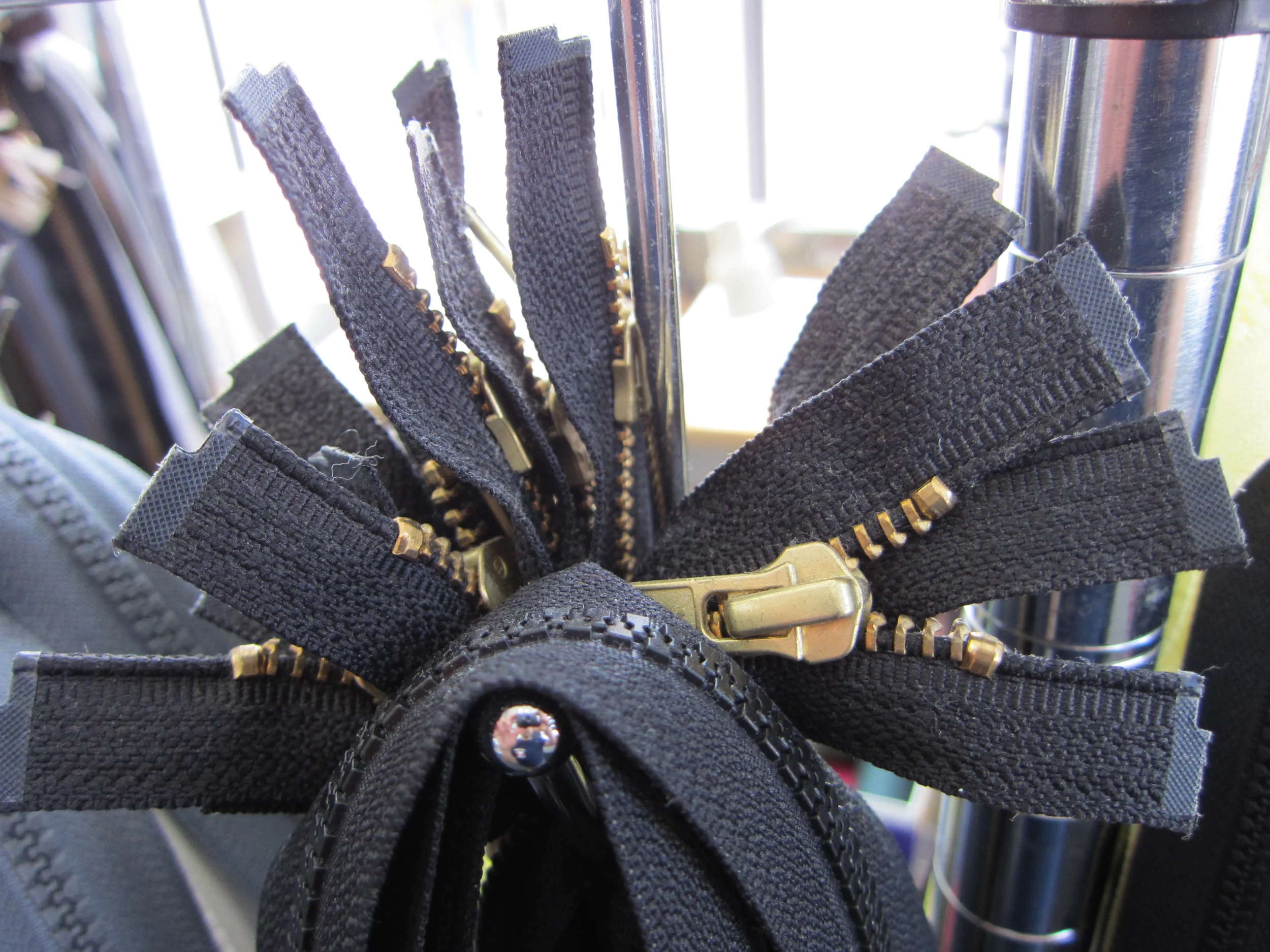 Close-up view of the zipper pulls and black fabric strips of a zipper in a wardrobe or clothing rack.