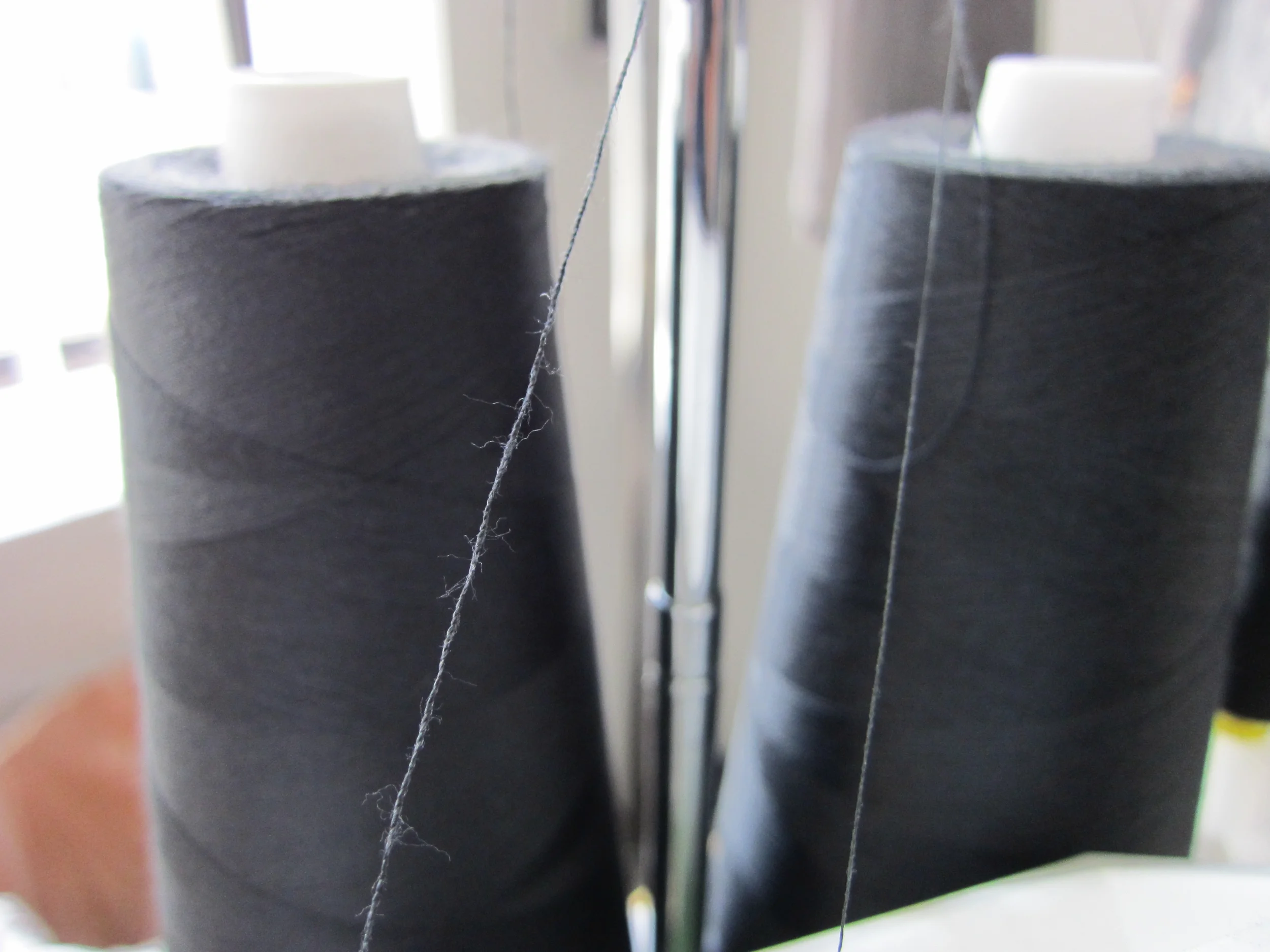 Close-up of a thin spider web strand between dark vertical objects.