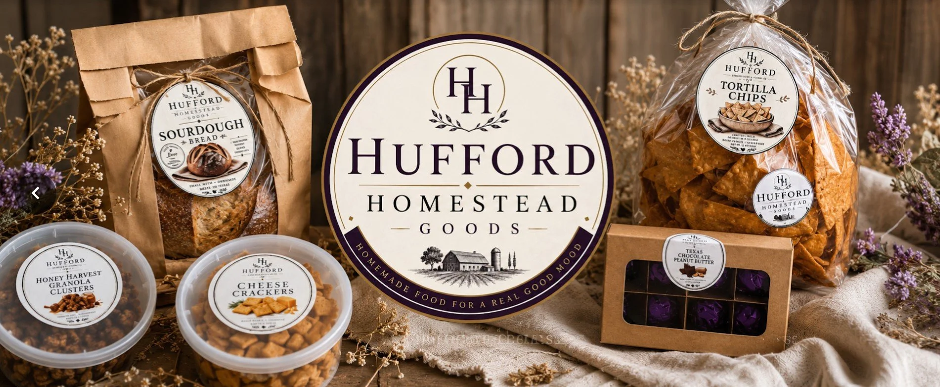 A display of Hufford Homestead Goods, including sourdough bread, honey harvest granola clusters, cheese crackers, tortilla chips, and Texas chocolate peanut butter. The products are arranged on a rustic surface with decorative flowers, and a large Hufford Homestead logo sign is centered among them.