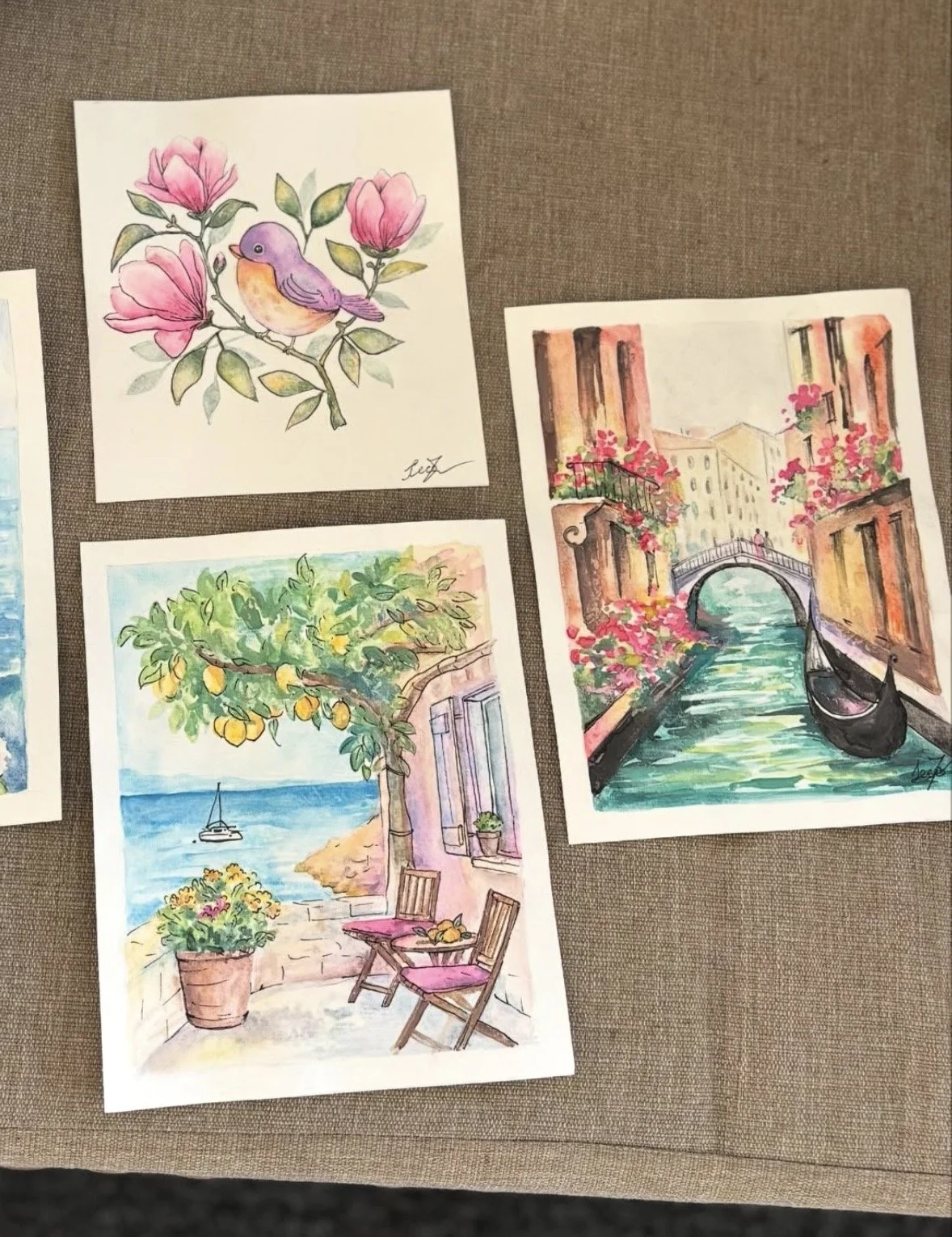 Collection of watercolor paintings including a pink bird on a branch with flowers, a canal scene with buildings and a bridge, a lemon tree with a boat in the water, and a seaside terrace with chairs and a potted plant.