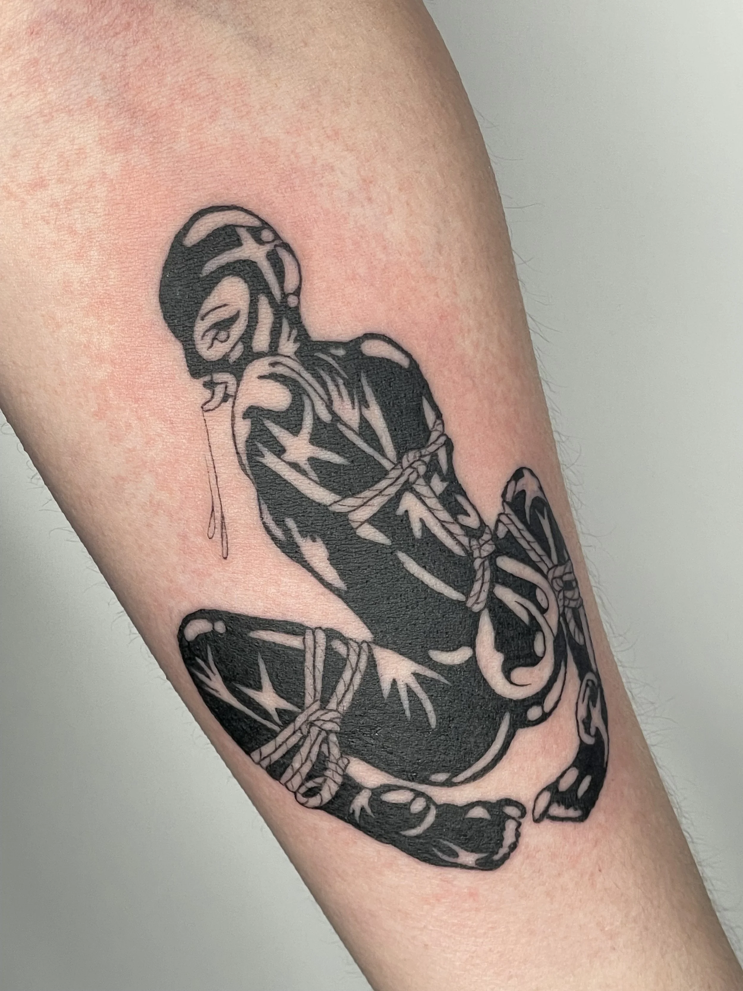 Tattoo of a skeleton on a person's arm with a black ink outline style. latex pinup.