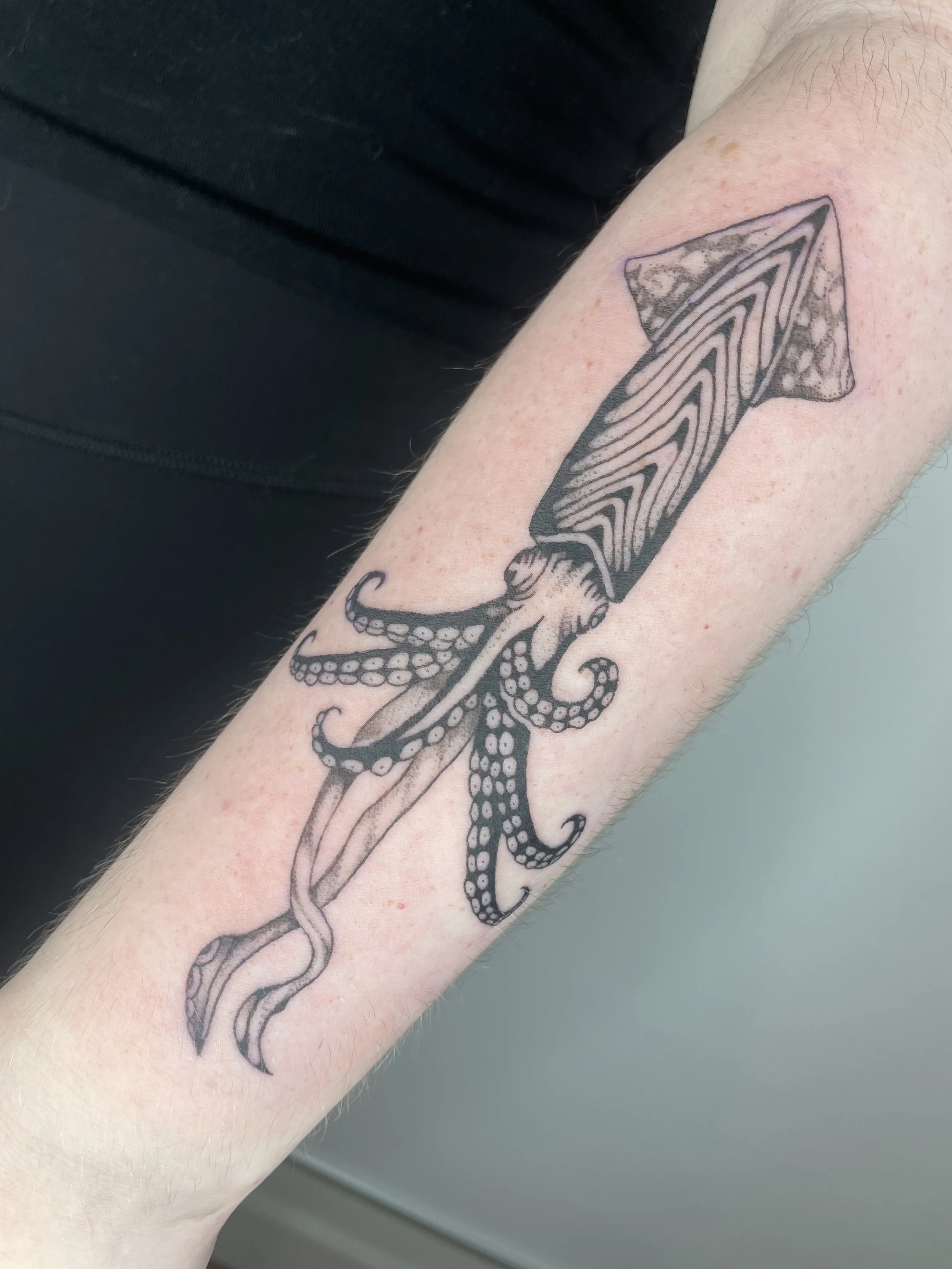 Tattoo of with a giant squid on a person's forearm.