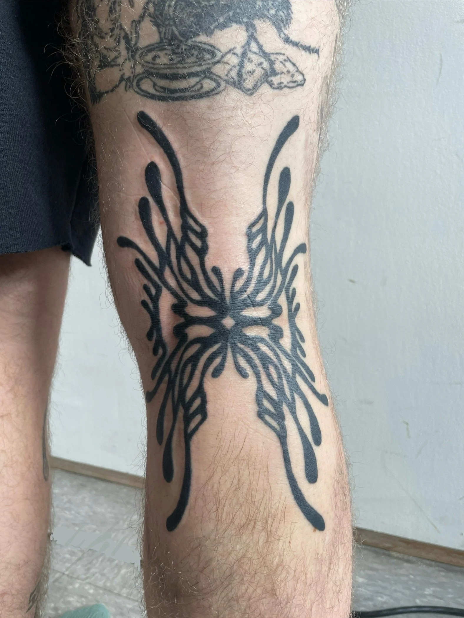Tattoo of a butterfly on a person's leg, with dragonfly silhouettes on the foot and ankle.