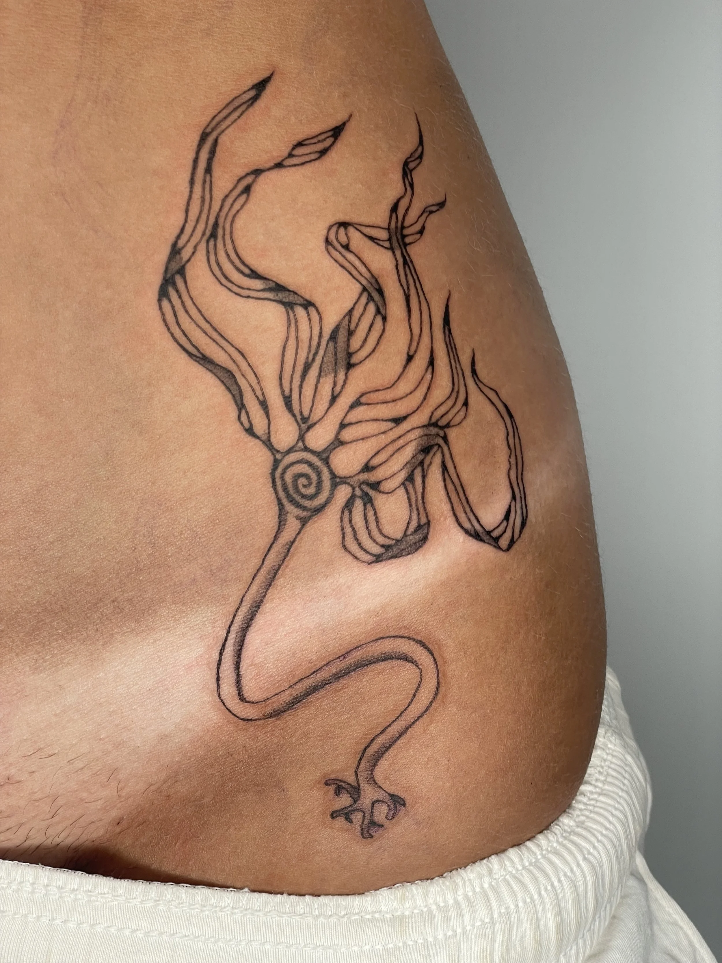 Tattoo of a stylized, bull whip kelp on a person's shoulder and upper arm.