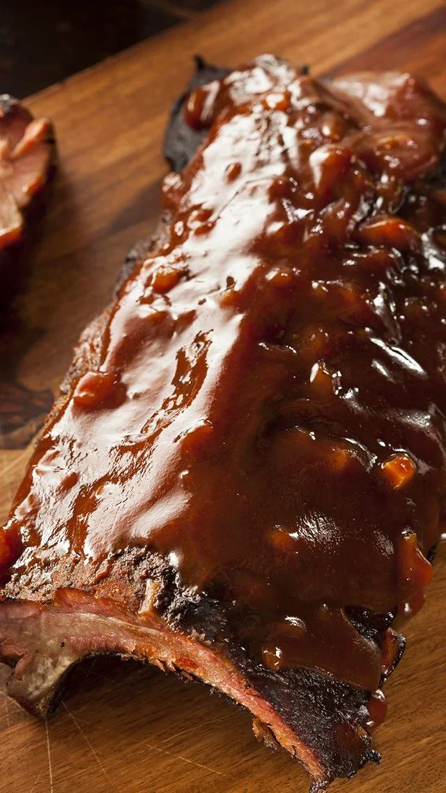 Barbecue ribs with sauce on a wooden cutting board.
