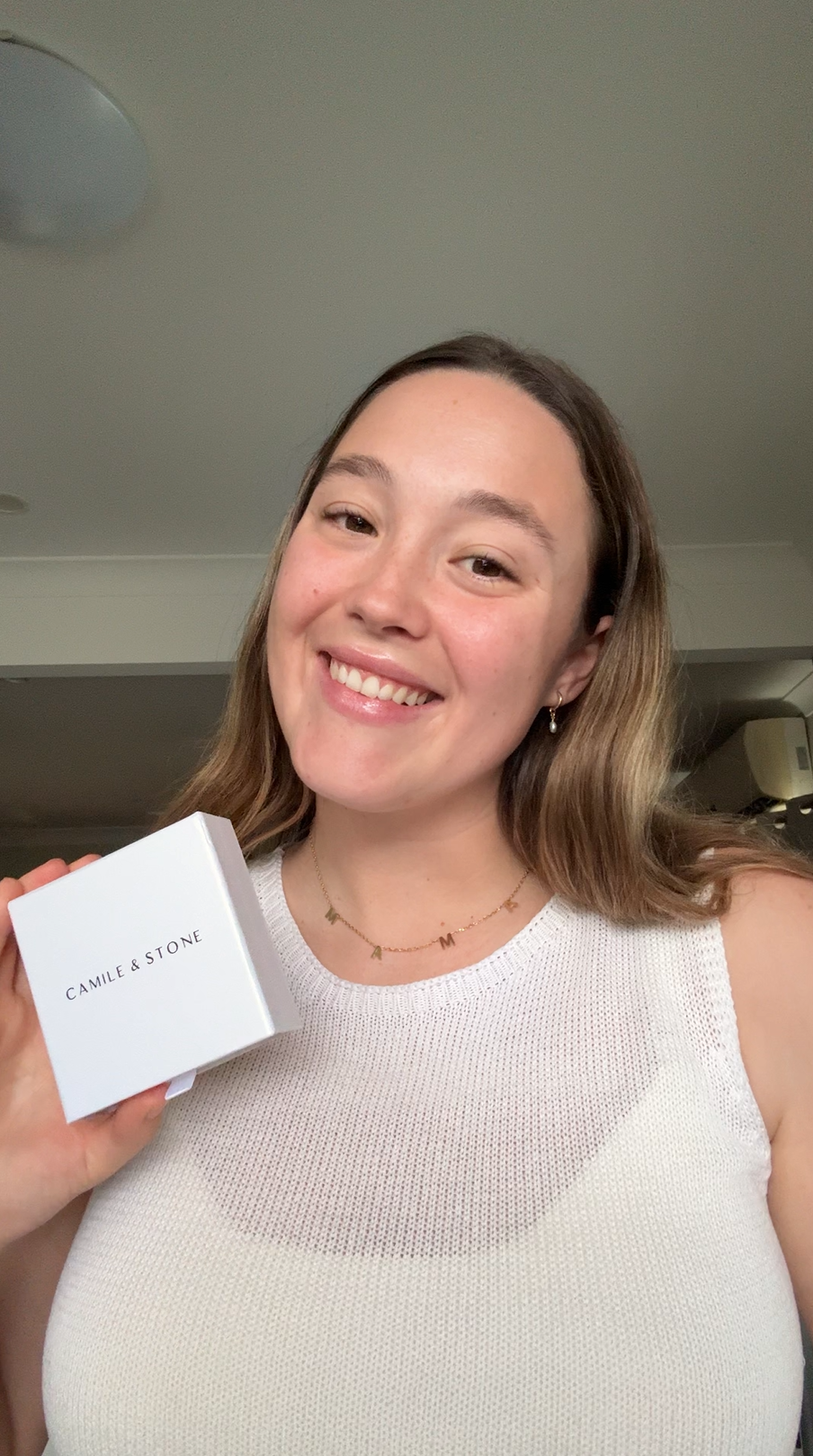Smiling woman holding a white box labeled 'Camille & Stone'