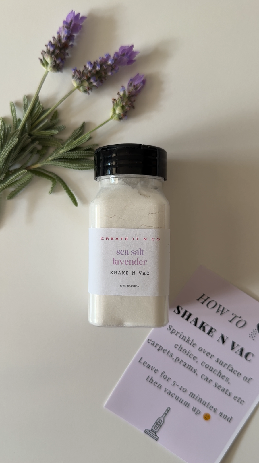 A small jar of sea salt lavender shake n vac with a sprig of lavender flowers and a printed instruction sheet on a white surface.