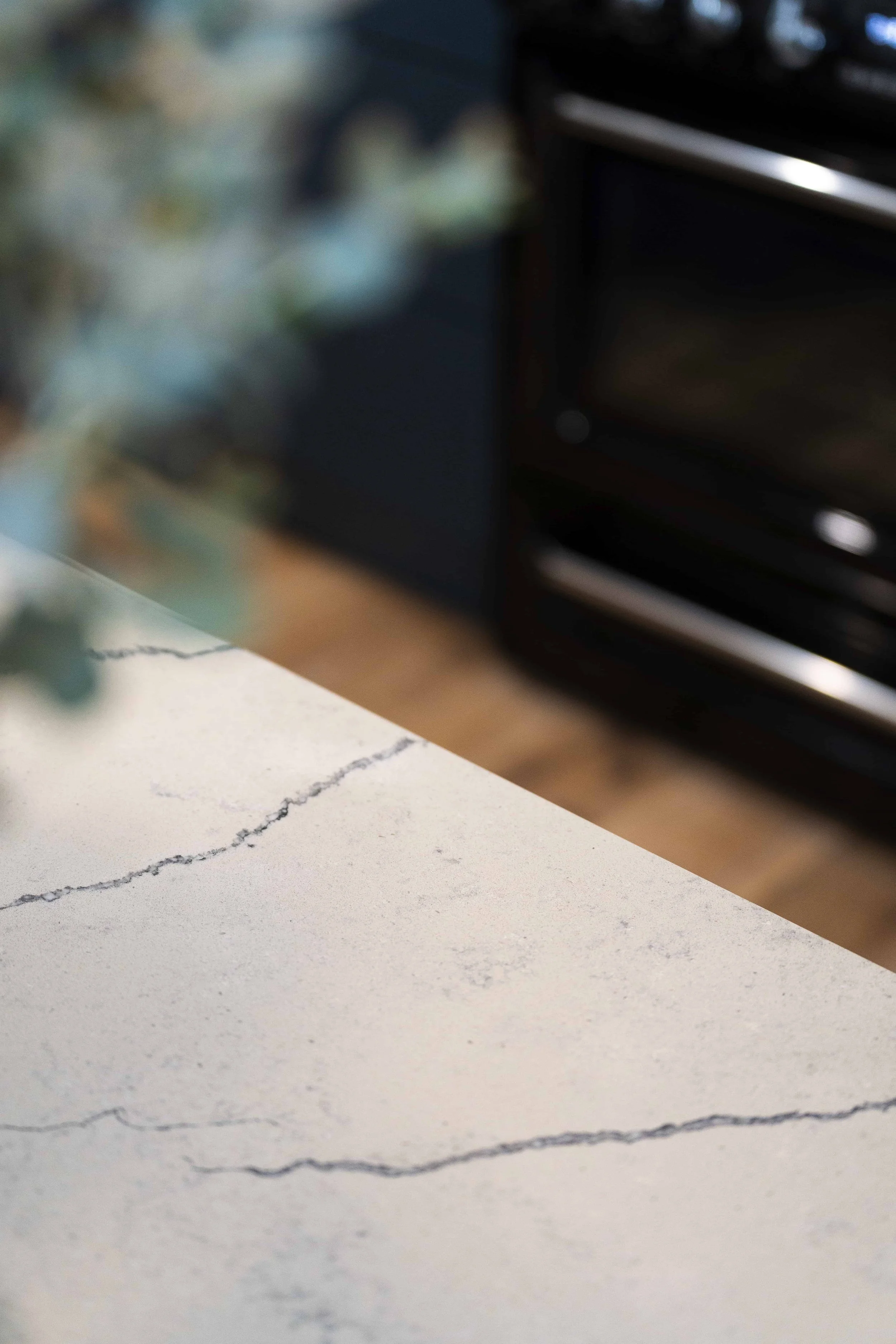 A close up of an island benchtop with a predominantly white bench with dark grey veins and pattern