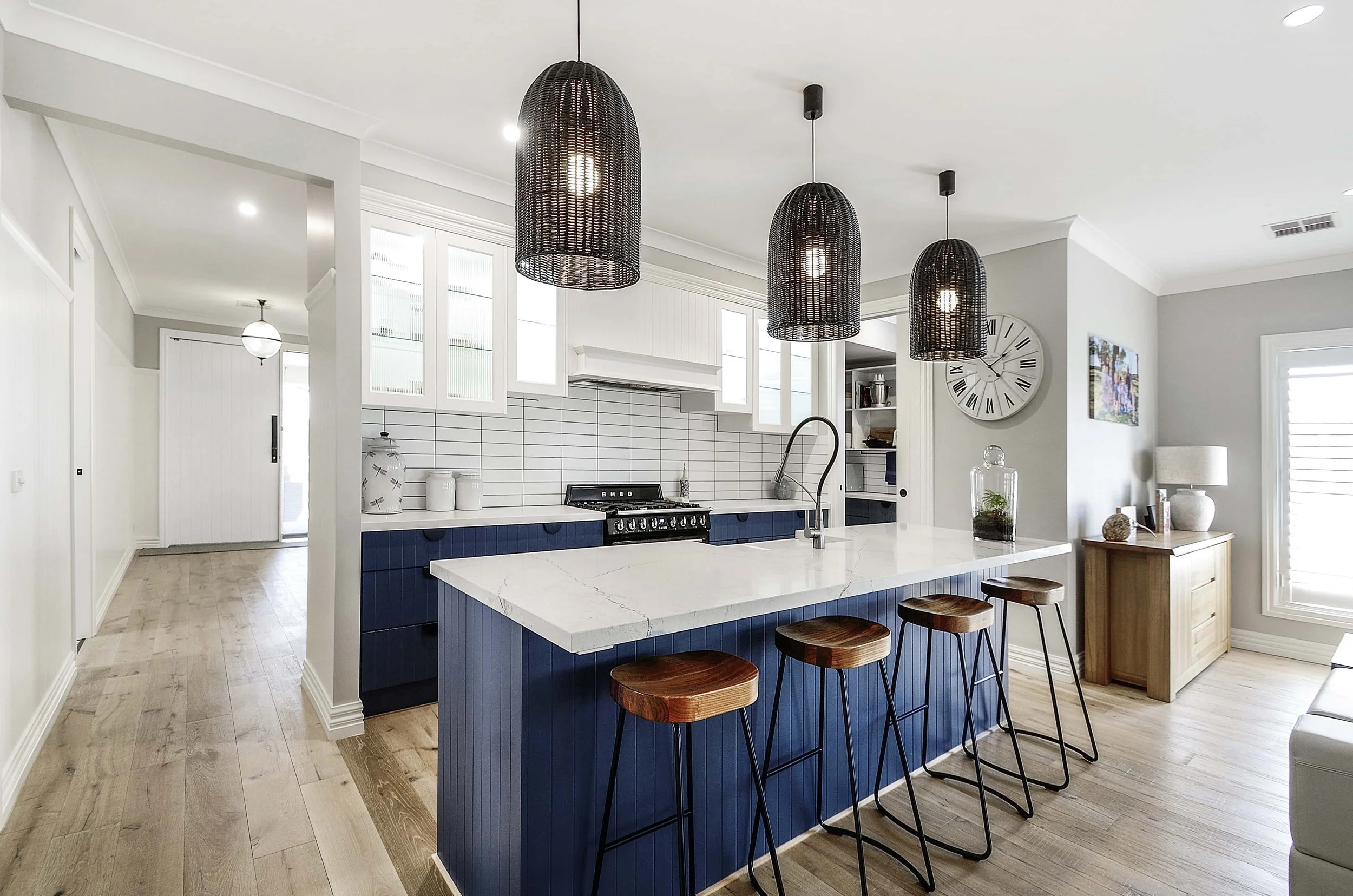 A dark blue kitchen with a natural stone benchtop is a stand out feature in a room with fresh bright tones.
