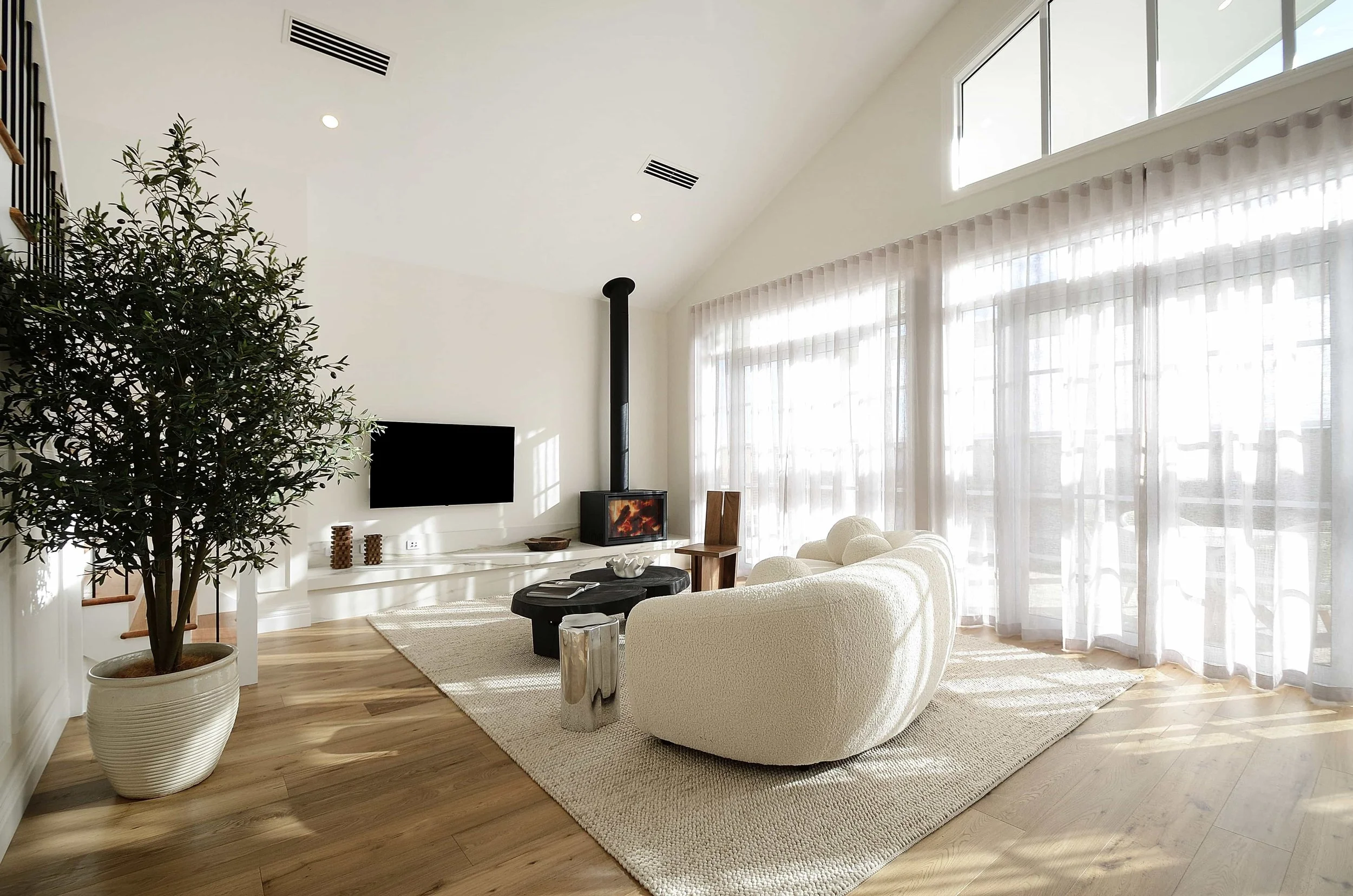 A contemporary light filled living area with a fireplace and cathedral ceiling.