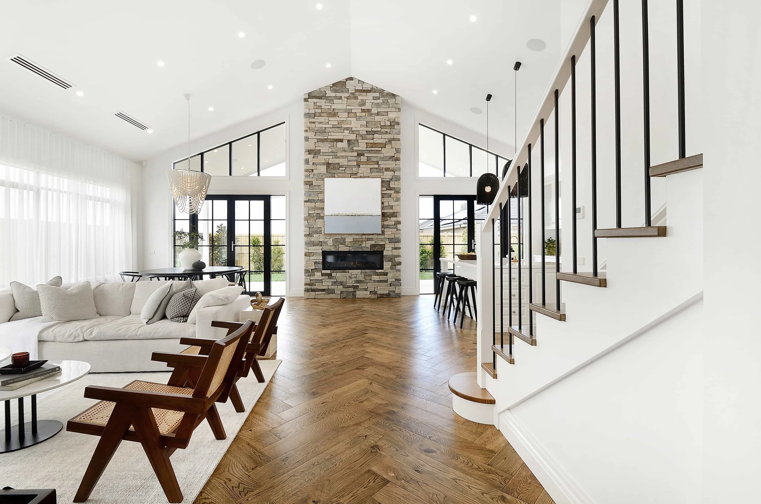 A contemporary open living area with a cathedral ceiling and fireplace.