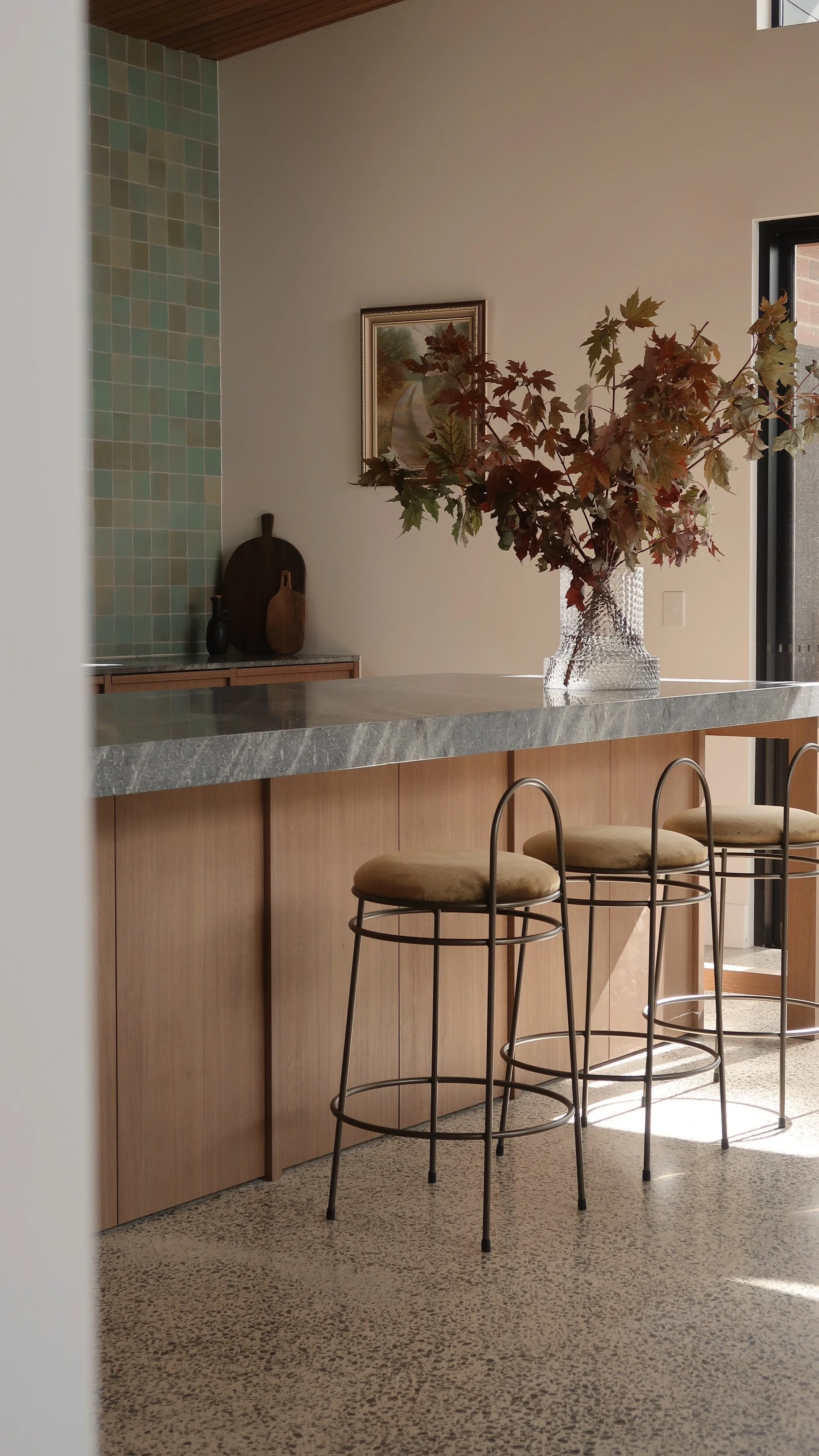 A beautiful custom timber kitchen with a natural stone benchtop, green wall tiles, and feature timber ceiling lining in an eclectic custom home.