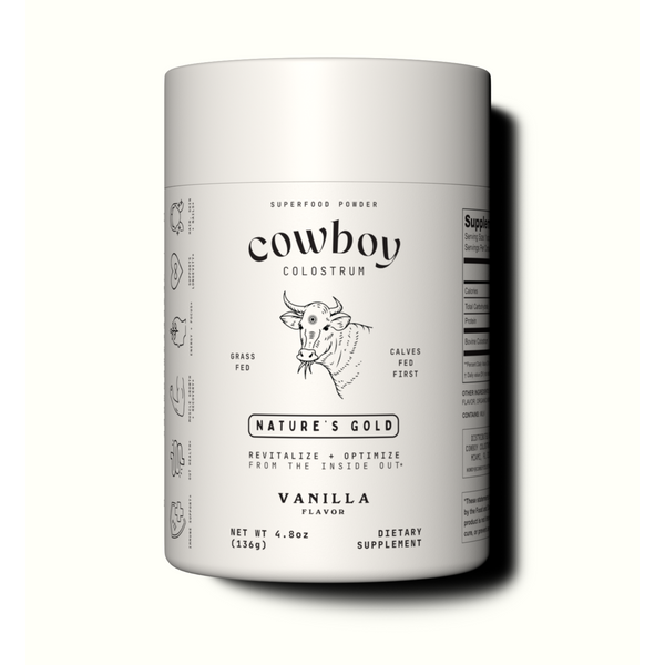 A container of Cowboy Colostrum Superfood Powder, vanilla flavor, with illustrations of cow parts and health benefits on the label.