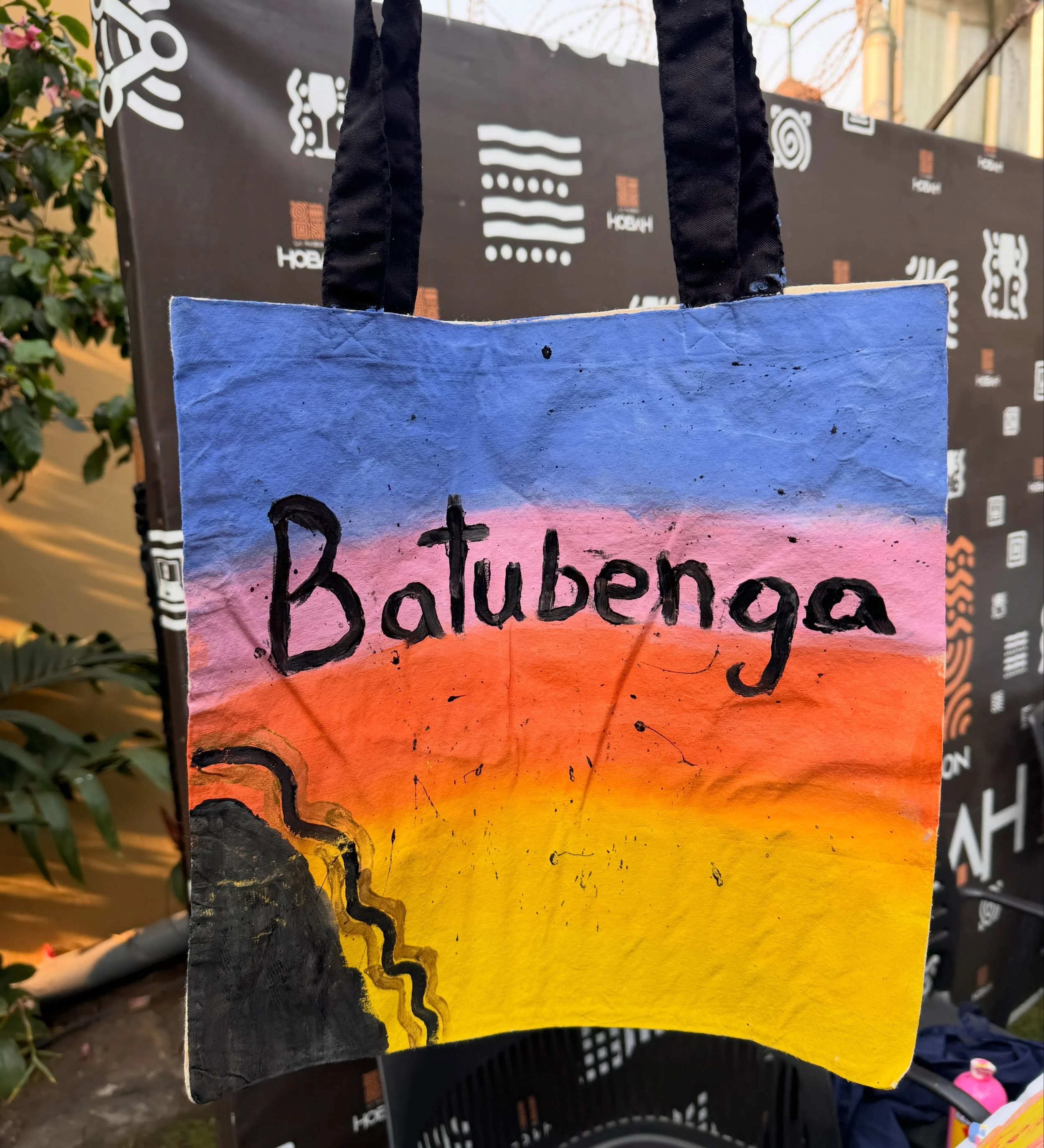 Colorfully painted protest sign with the words 'Baltimore' and a stylized skyline against a sunset background, featuring a black outline of a snake and black handwritten text.