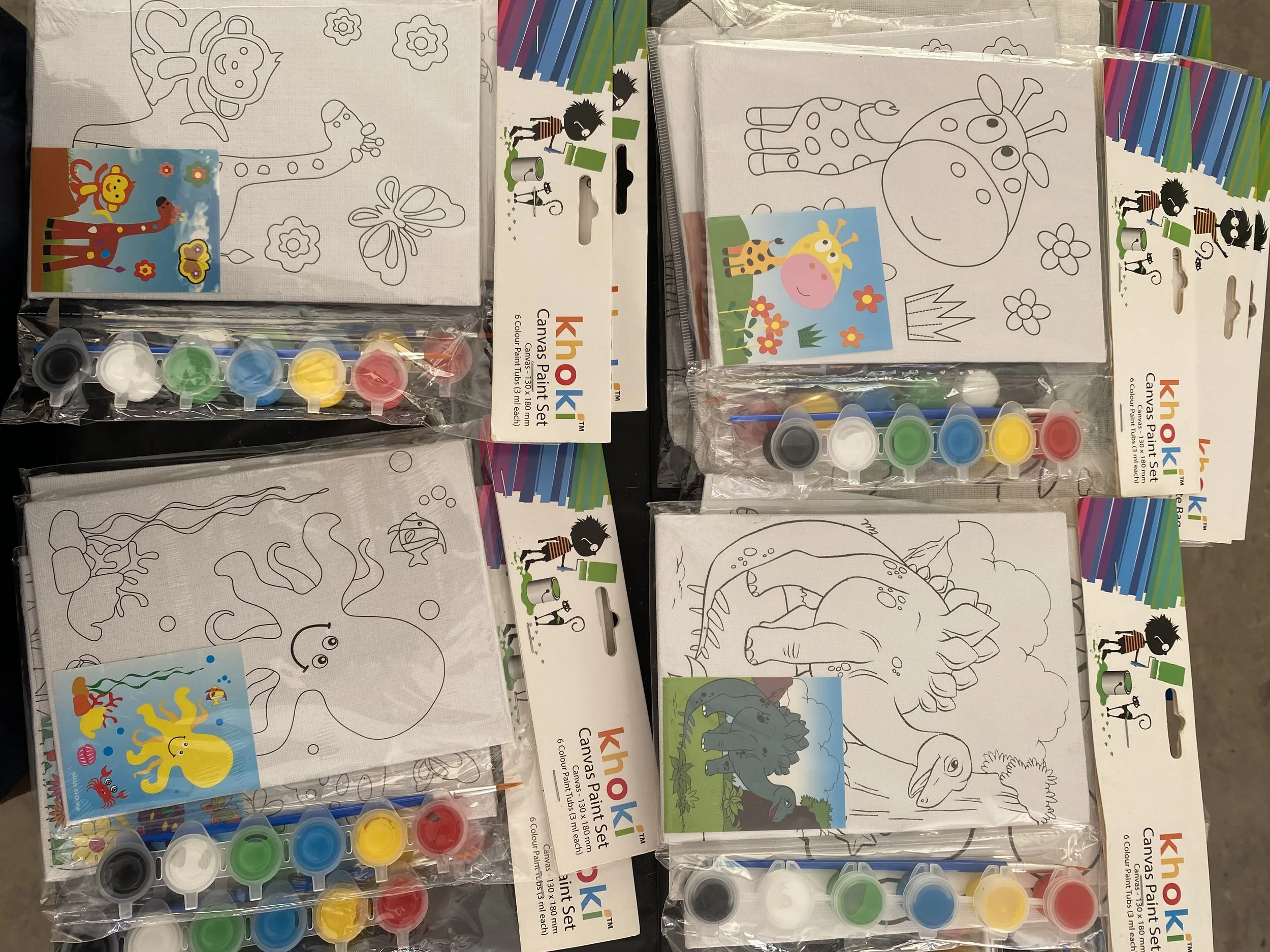 Colorful paint sets with blank animal-themed canvas sheets for painting, featuring various animal outlines such as a dinosaur, giraffe, and cow, along with stickers and brushes.