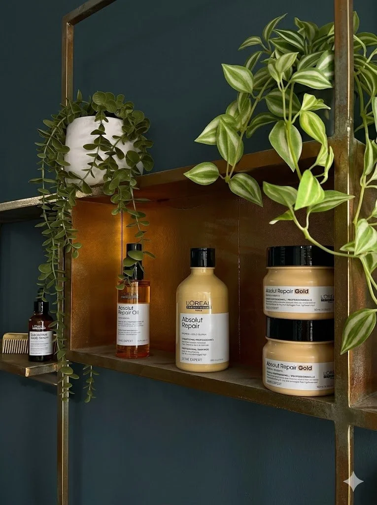 A wooden wall shelf with green potted plants and bottles of L'Oreal Absolut Repair hair products.