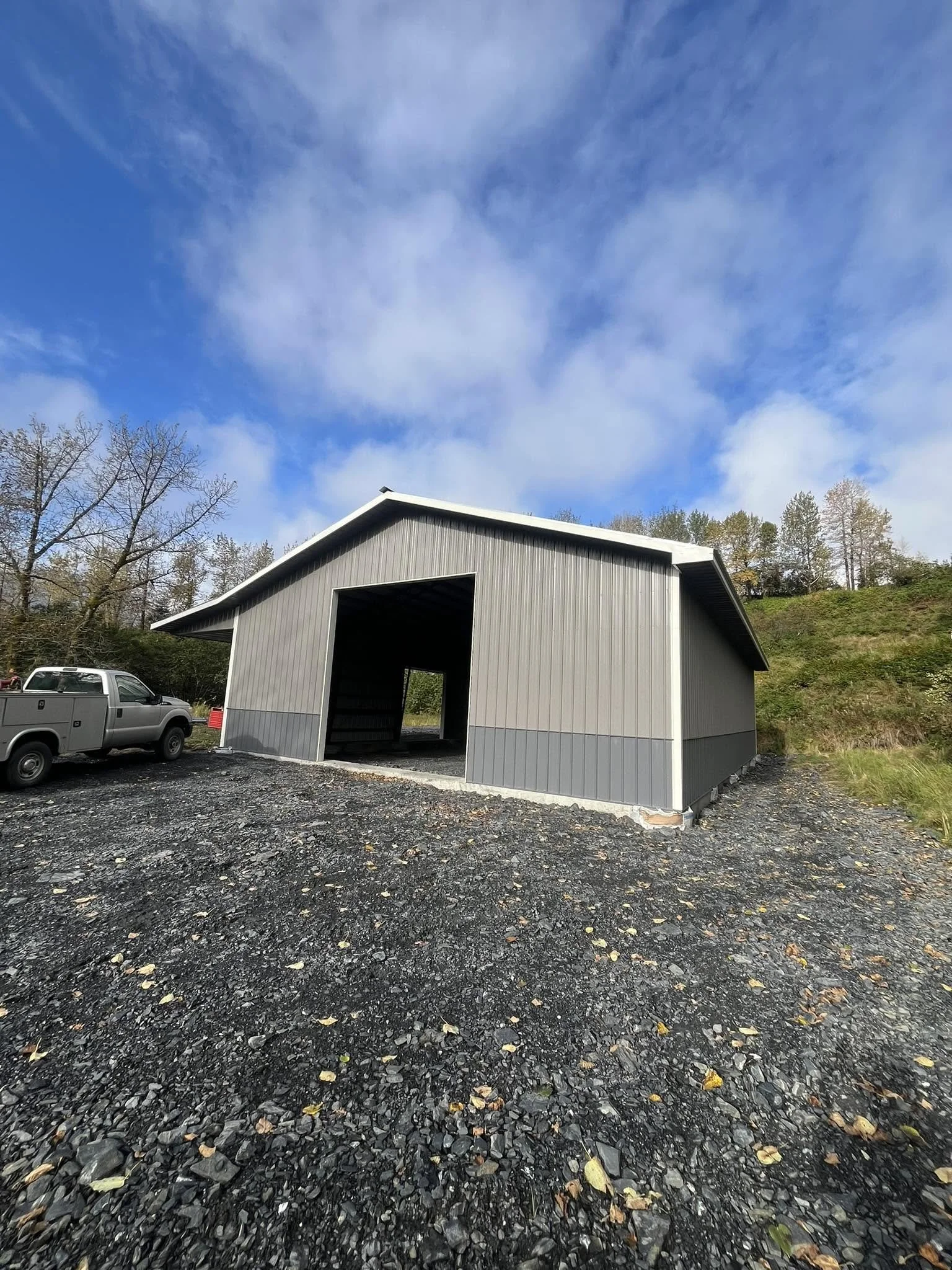 Completed metal building with gray siding and a large open entryway.