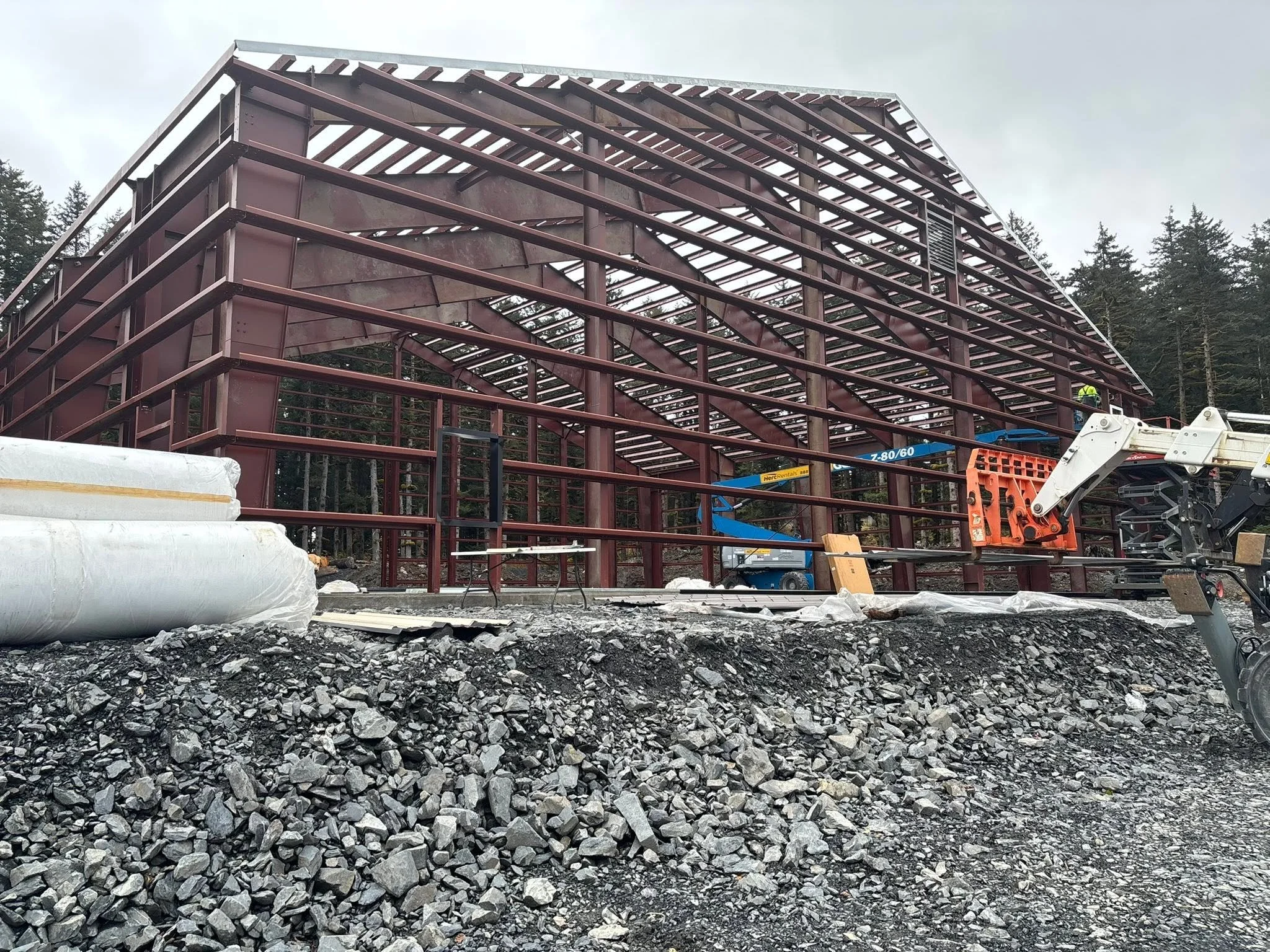 Steel-frame building under construction with exposed structural beams and construction equipment.