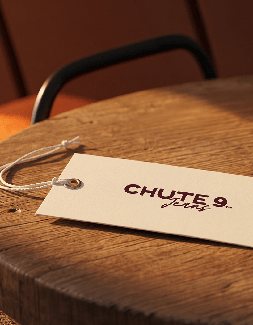 A white clothing tag labeled 'Chute 9 Jeans' resting on a wooden table.