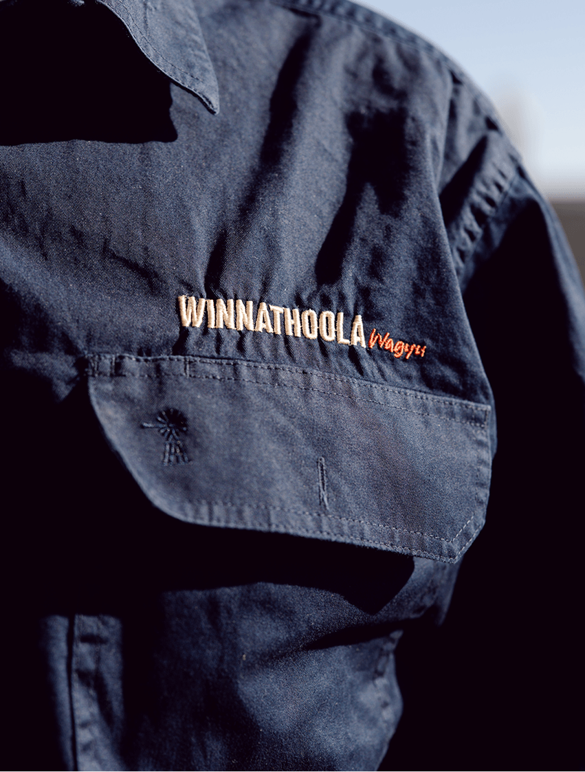A navy blue uniform shirt with an embroidered patch reading 'WINNATHOOLA Wagyu' on the upper chest pocket.