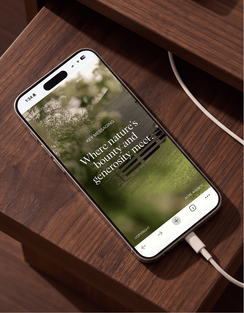 Smartphone on a wooden table displaying a website with the text "Where nature's bounty and generosity meet." and connected to a charging cable.