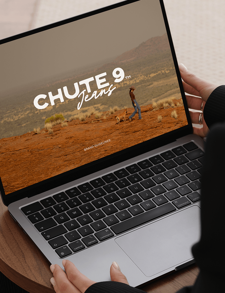 Laptop displaying the Chute 9 Jeans brand guidelines with a desert landscape and a woman walking her dog.