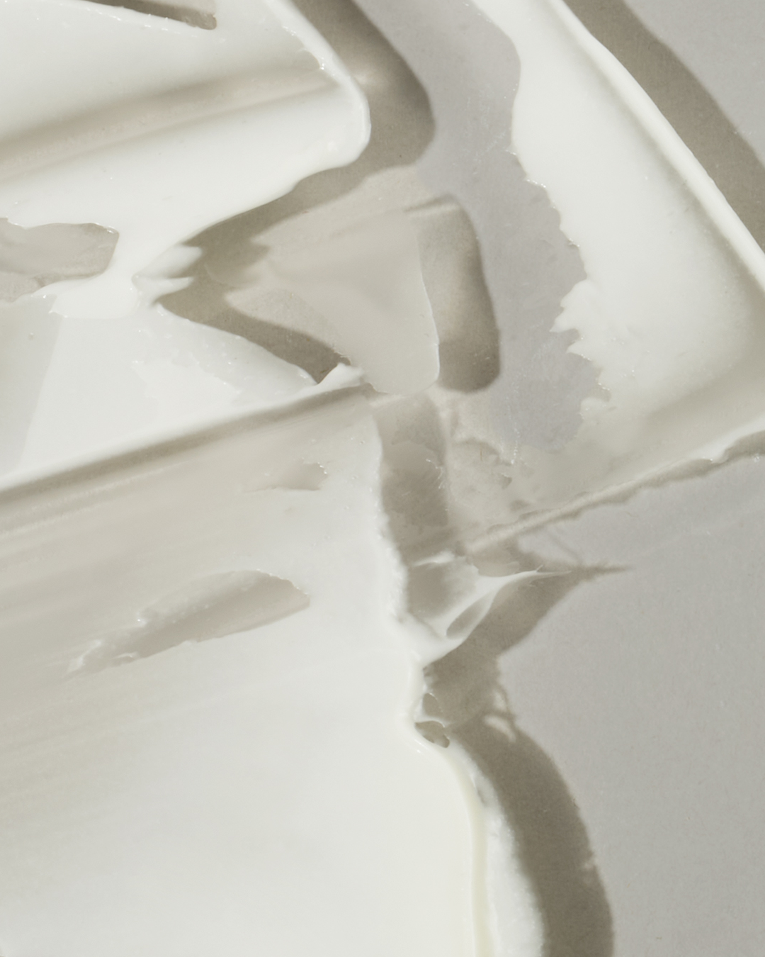 Close-up of an off-white cream face moisturizer being spread on a surface with a spatula.