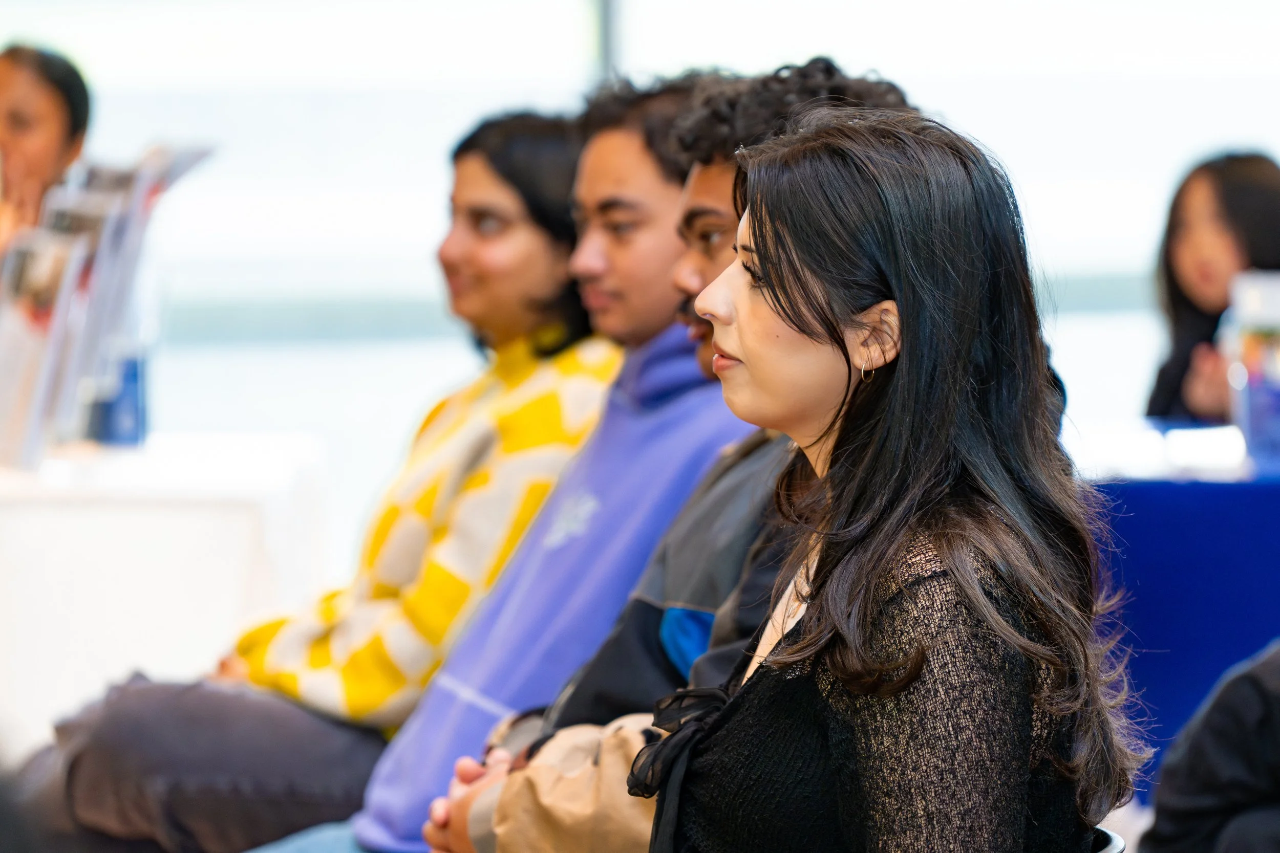 A group of diverse women sitting in a row, facing forward, in what appears to be a classroom or conference setting.