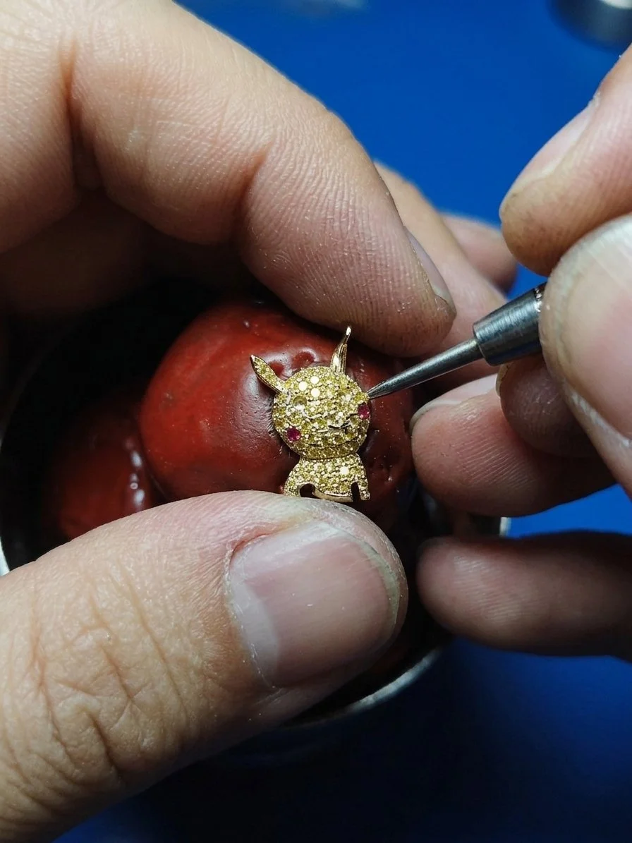 Artisan handcrafting a bespoke 18k gold and yellow sapphire pavé pendant inspired by a child’s drawing for Teeny Atelier