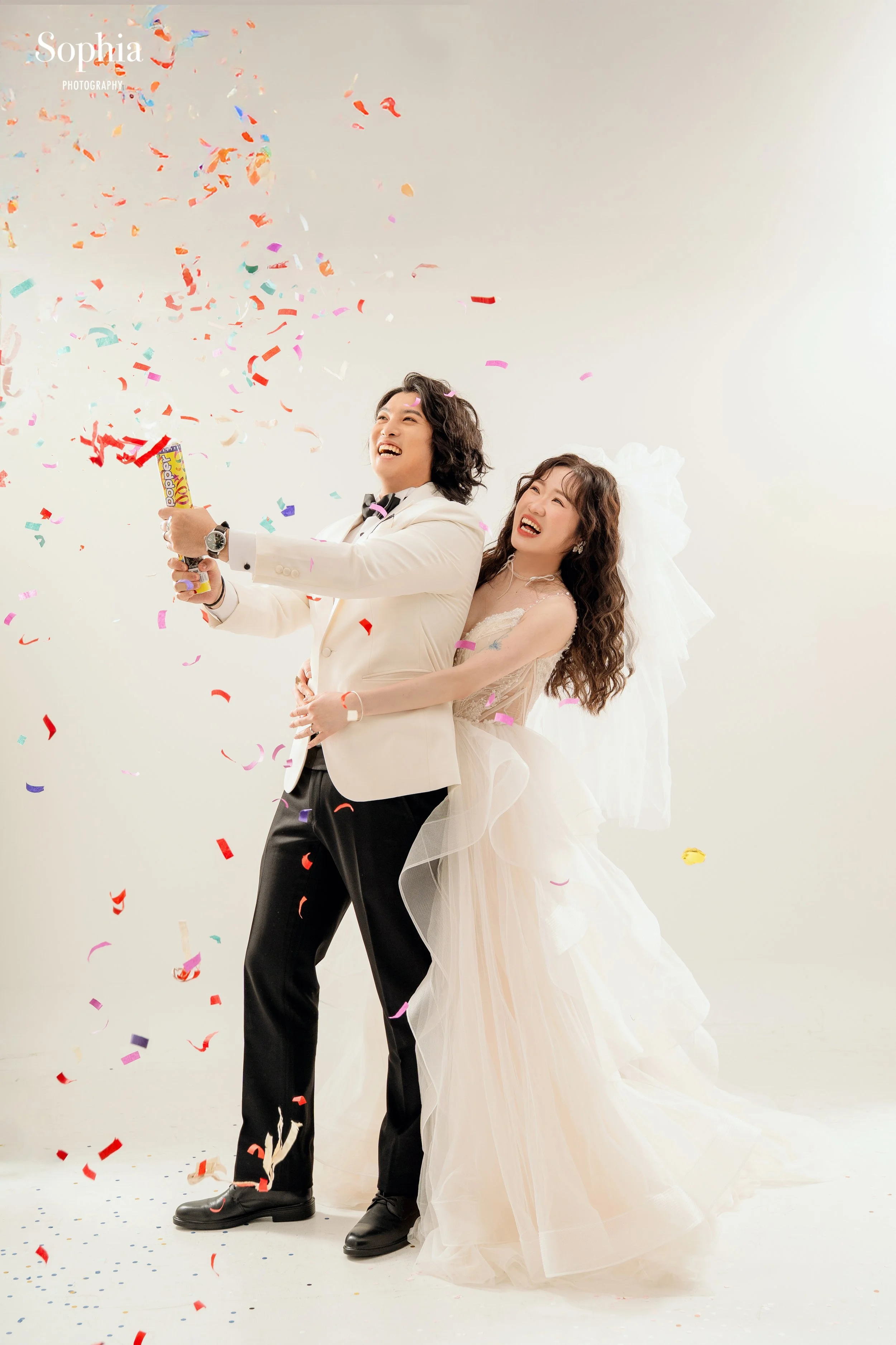 歡樂風格棚拍婚紗，新人在彩色紙花中自然大笑互動