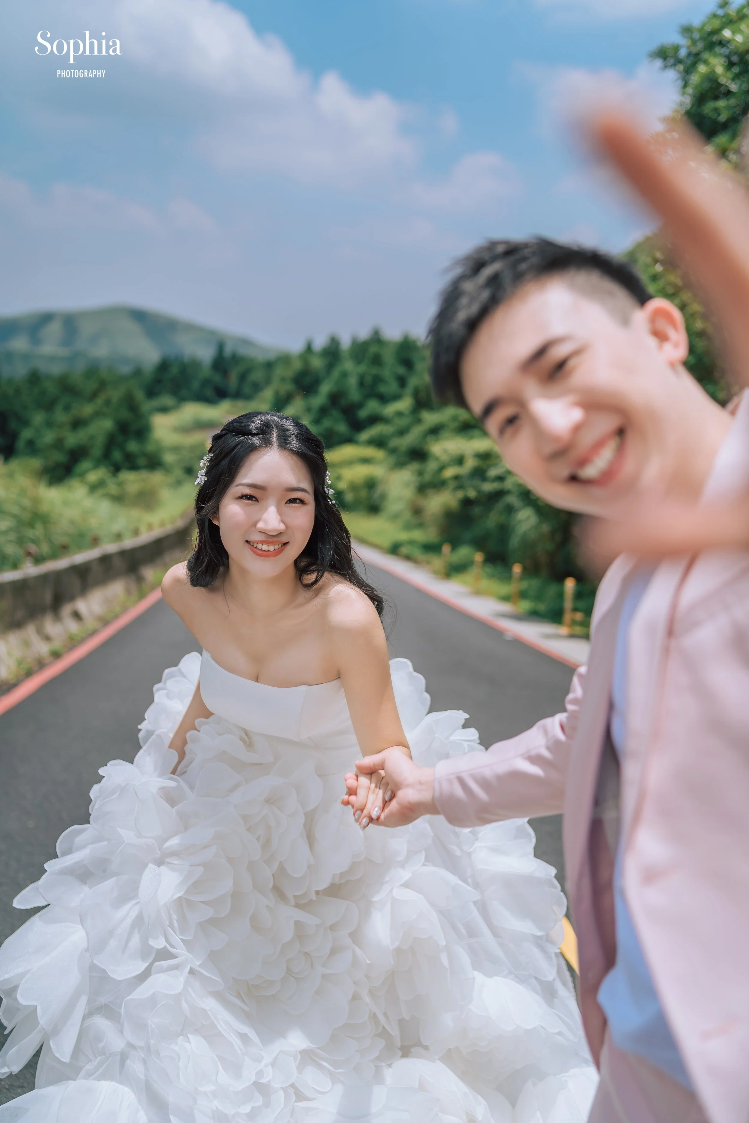 戶外公路婚紗攝影，新人在山景道路上牽手互動，呈現自然活潑的婚紗照