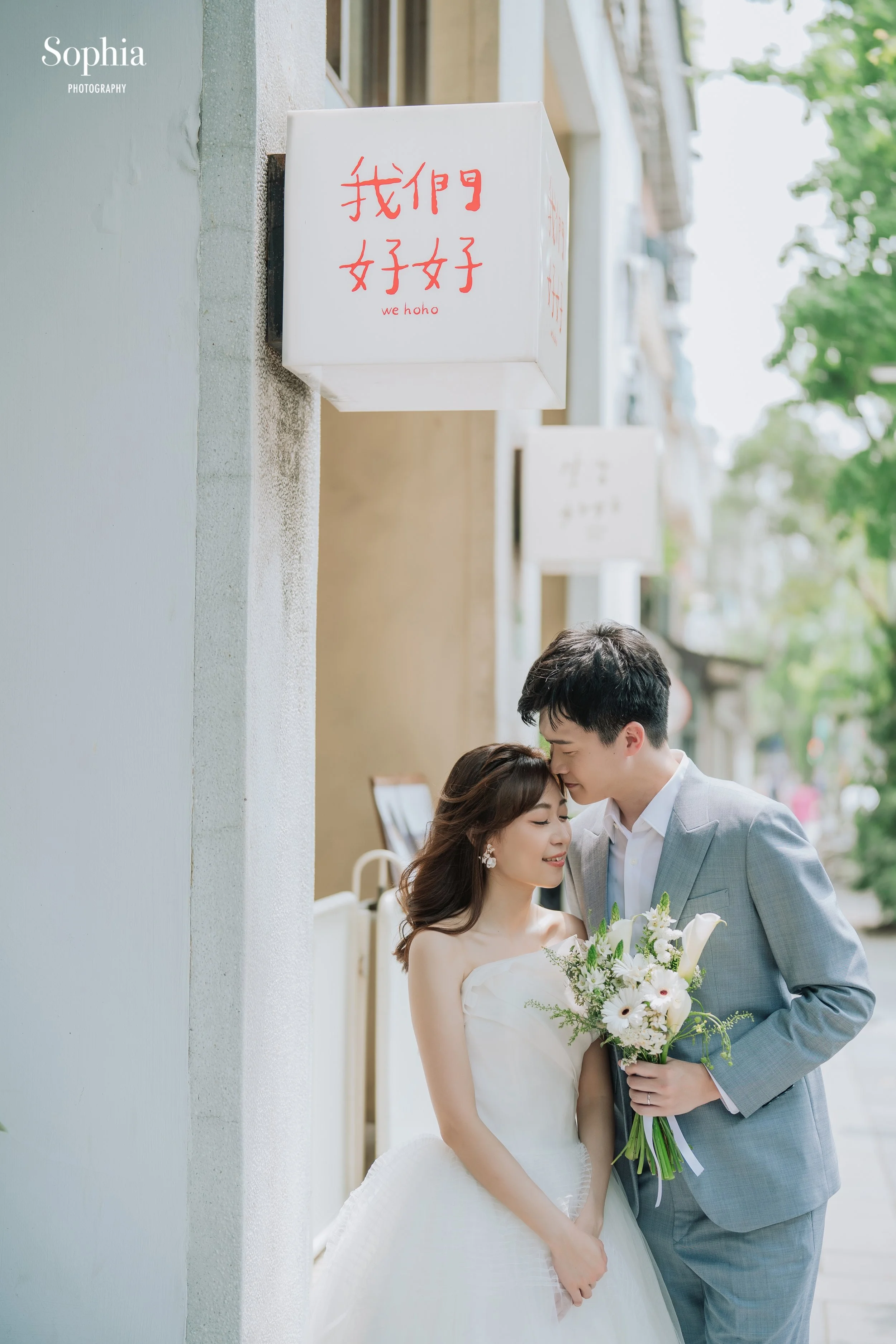 城市街景婚紗攝影，新人穿著白紗與灰色西裝在巷弄中自然靠近