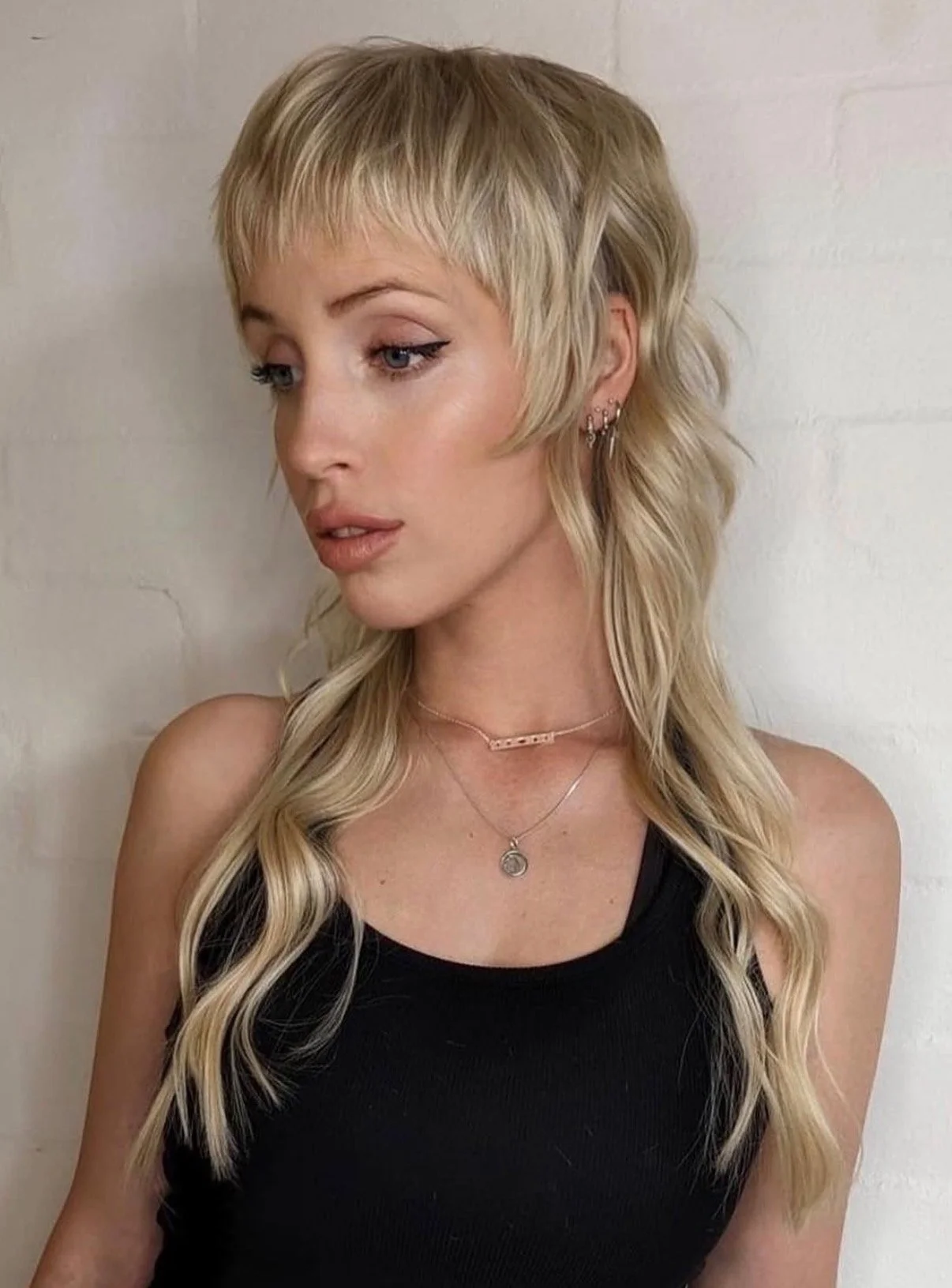 A woman with Blonde hair colour and styled with fringe and toned, wearing black singlet
