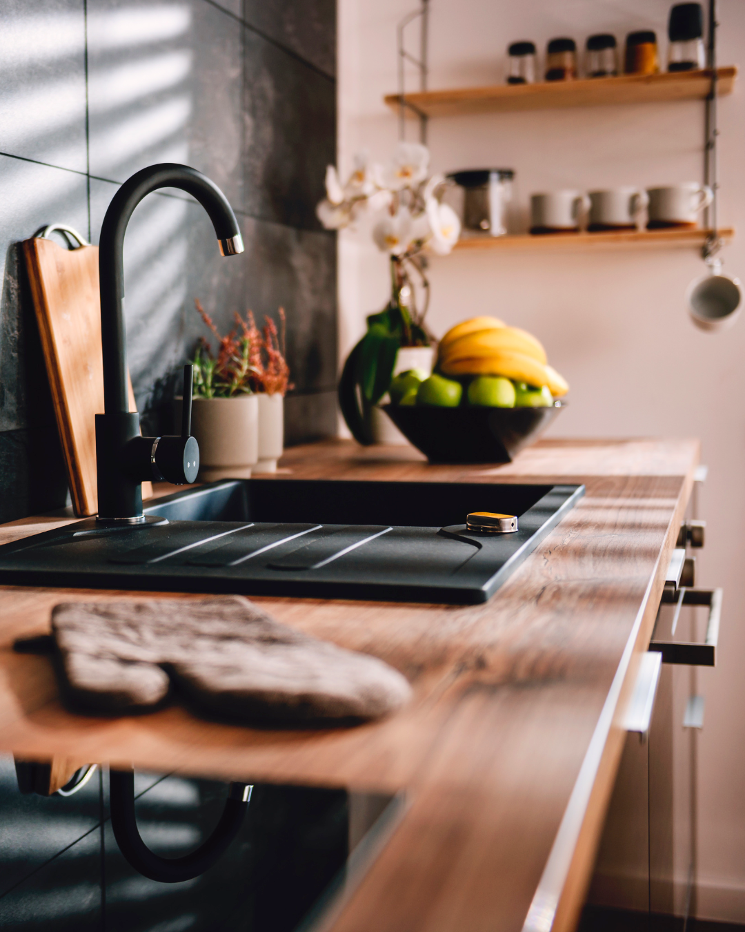 Modern kitchen with wooden countertops, black sink, open shelving and natural light.