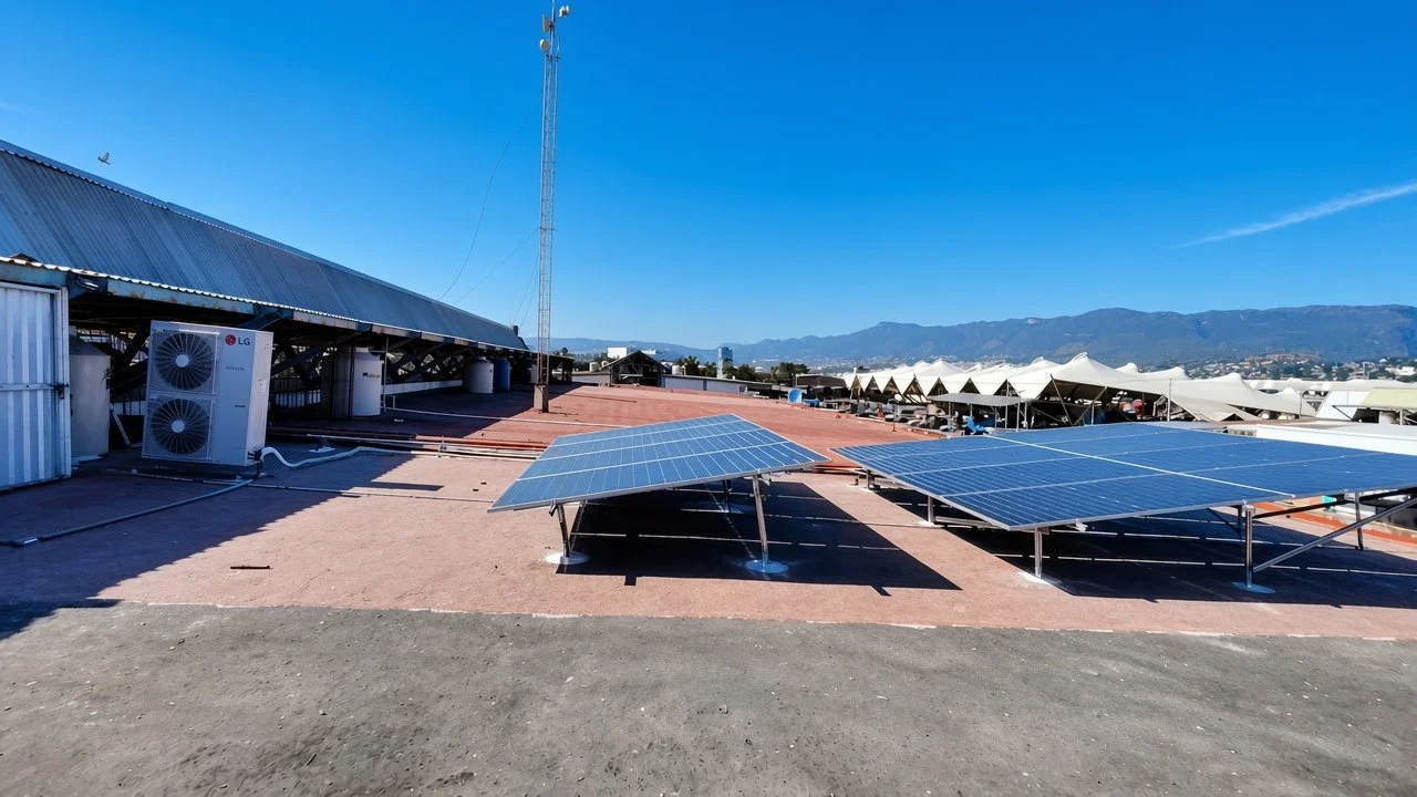 Paneles solares instalados en un techo con cielo despejado y montañas al fondo.