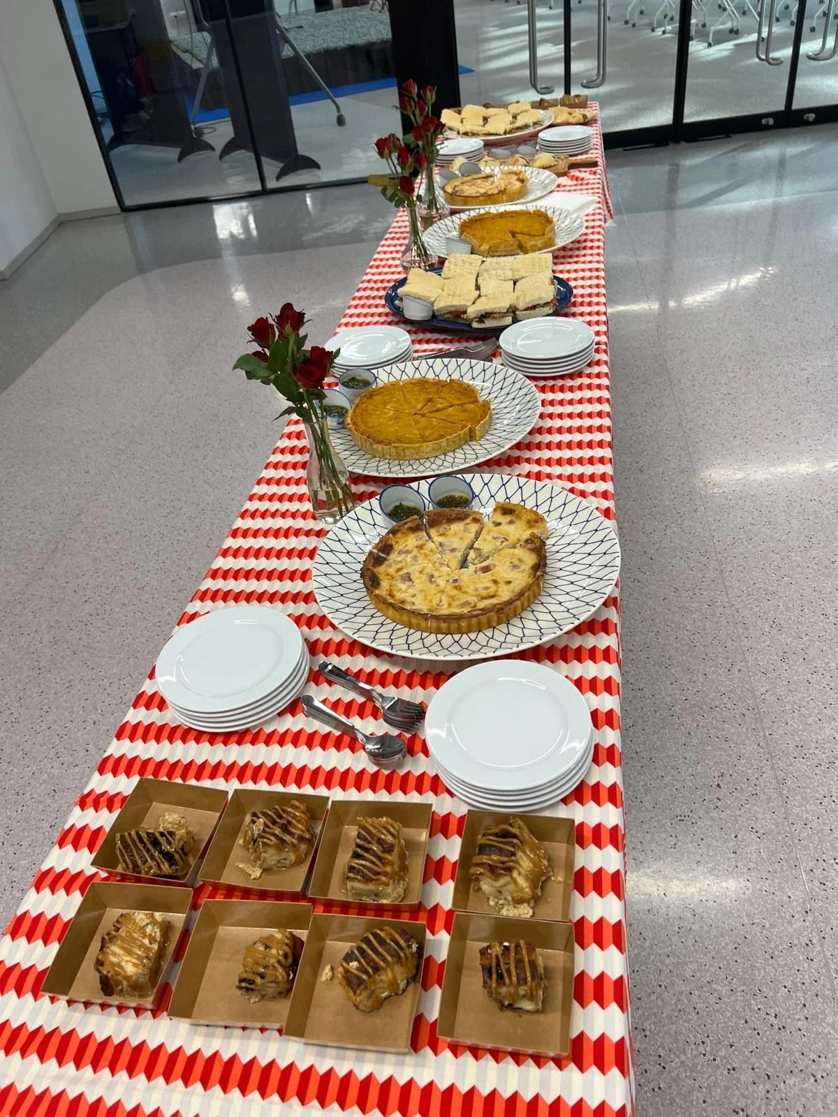 A long catering table with quiches, sandwiches and bread pudding