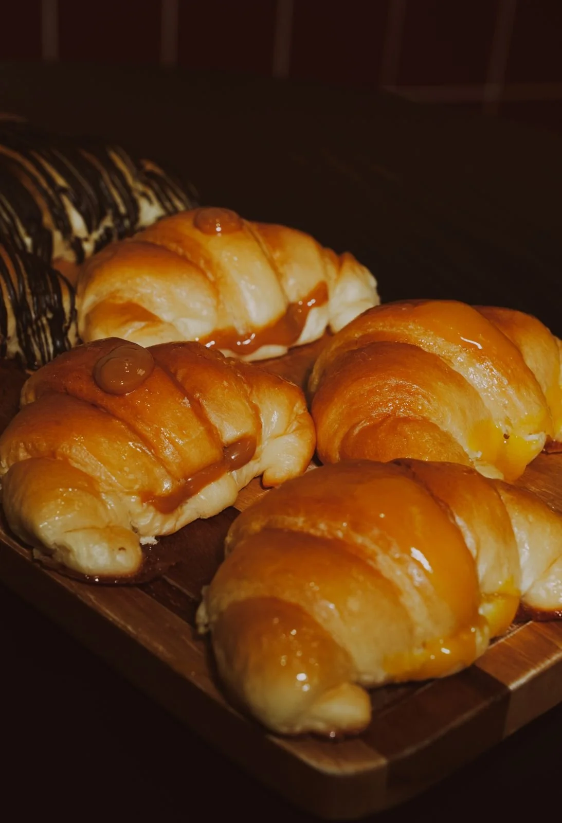Glazed crioche croissants on a wooden board