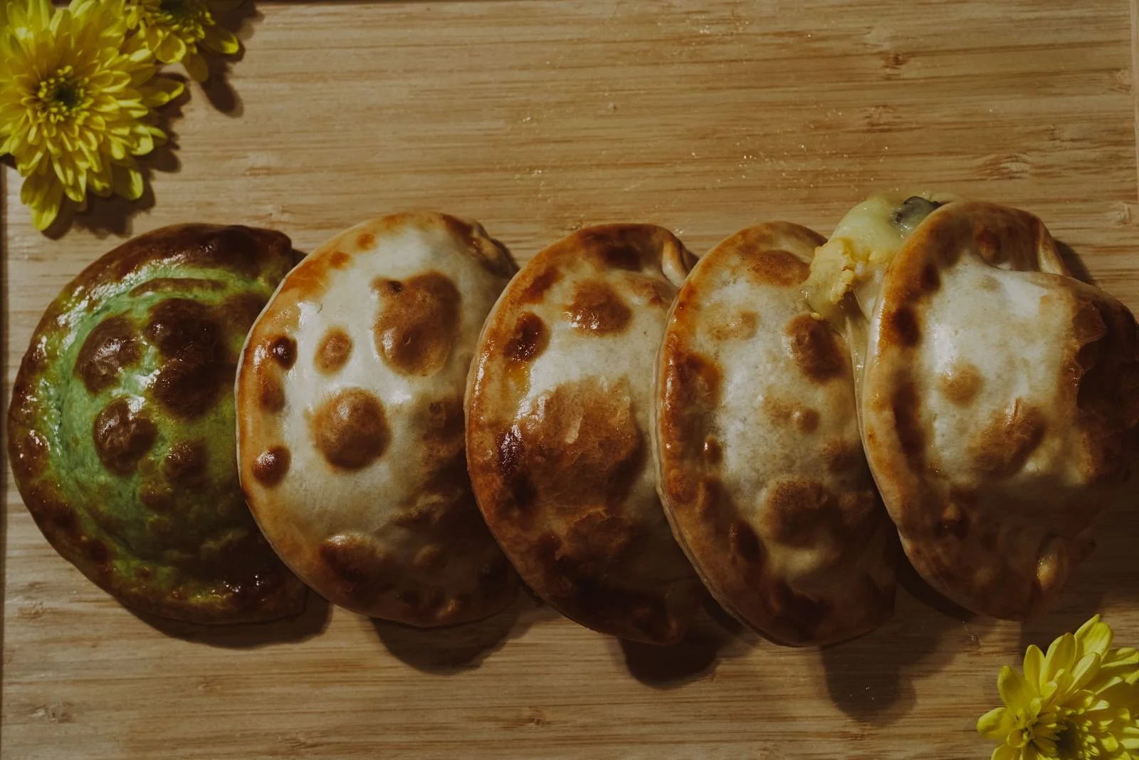 A row of golden baked empanadas on a wooden tray