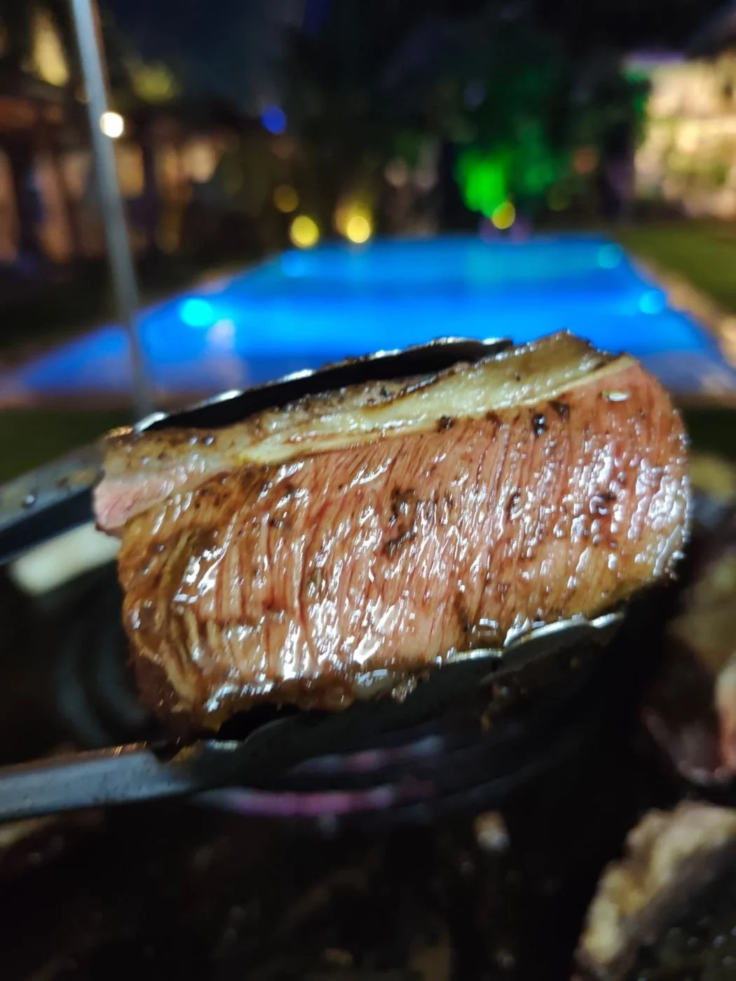 A juicy slice of grilled beef held in tongs