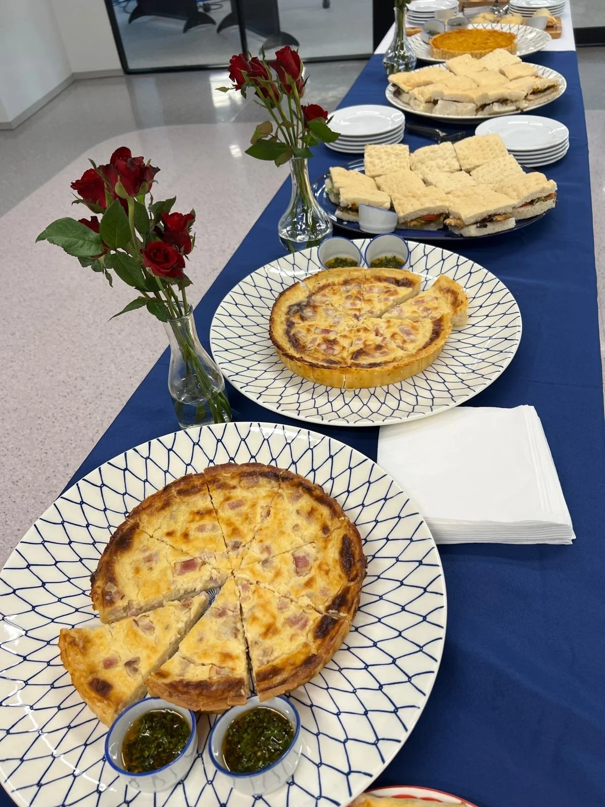 Ham and bacon quiches with chimichurri, focaccia sandwiches and red roses on a Mornii catering table