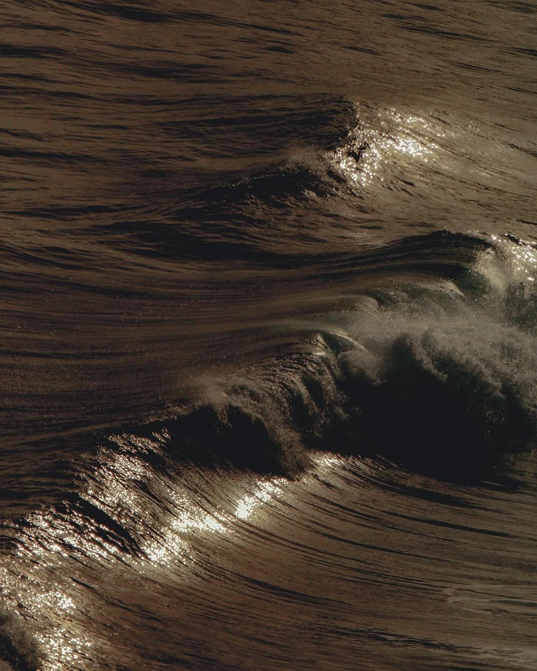 Close-up of ocean waves with sunlight reflecting off the surface at sunset or sunrise.