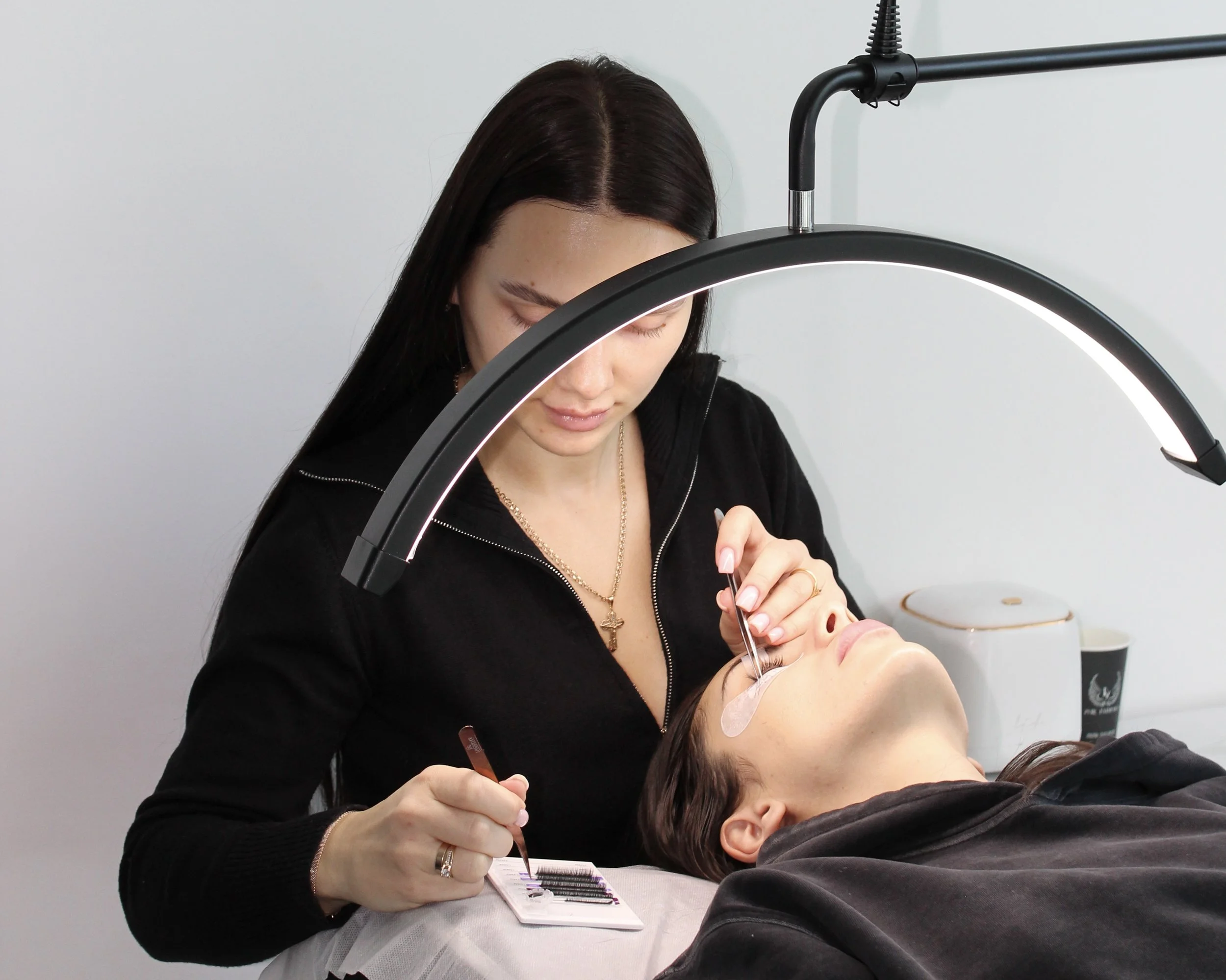 Lash and brow specialist working under a ring light