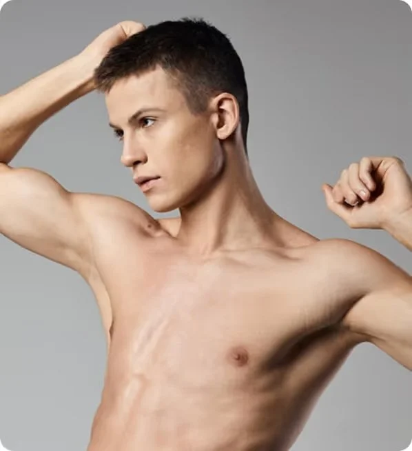 A shirtless young man with short dark hair posing with both arms flexed against a plain gray background.
